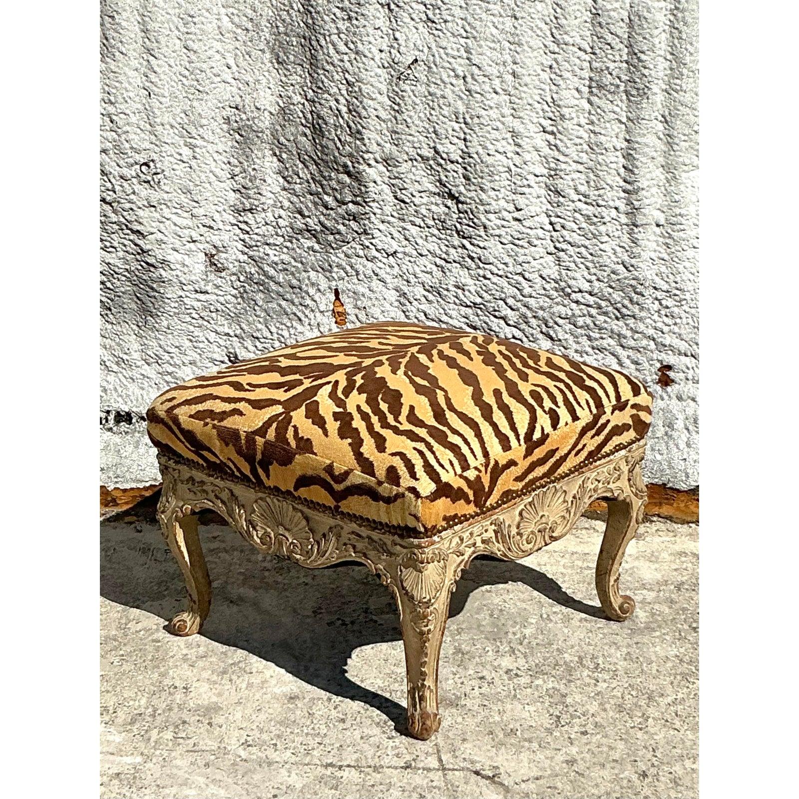 Porta nel tuo spazio un'eleganza senza tempo e un'audace raffinatezza con questo raffinato pouf Regency vintage, rivestito con l'iconico tessuto Scalamandré Le Tigre. Il lussuoso velluto con stampa tigrata emana opulenza e grandezza, mentre la
