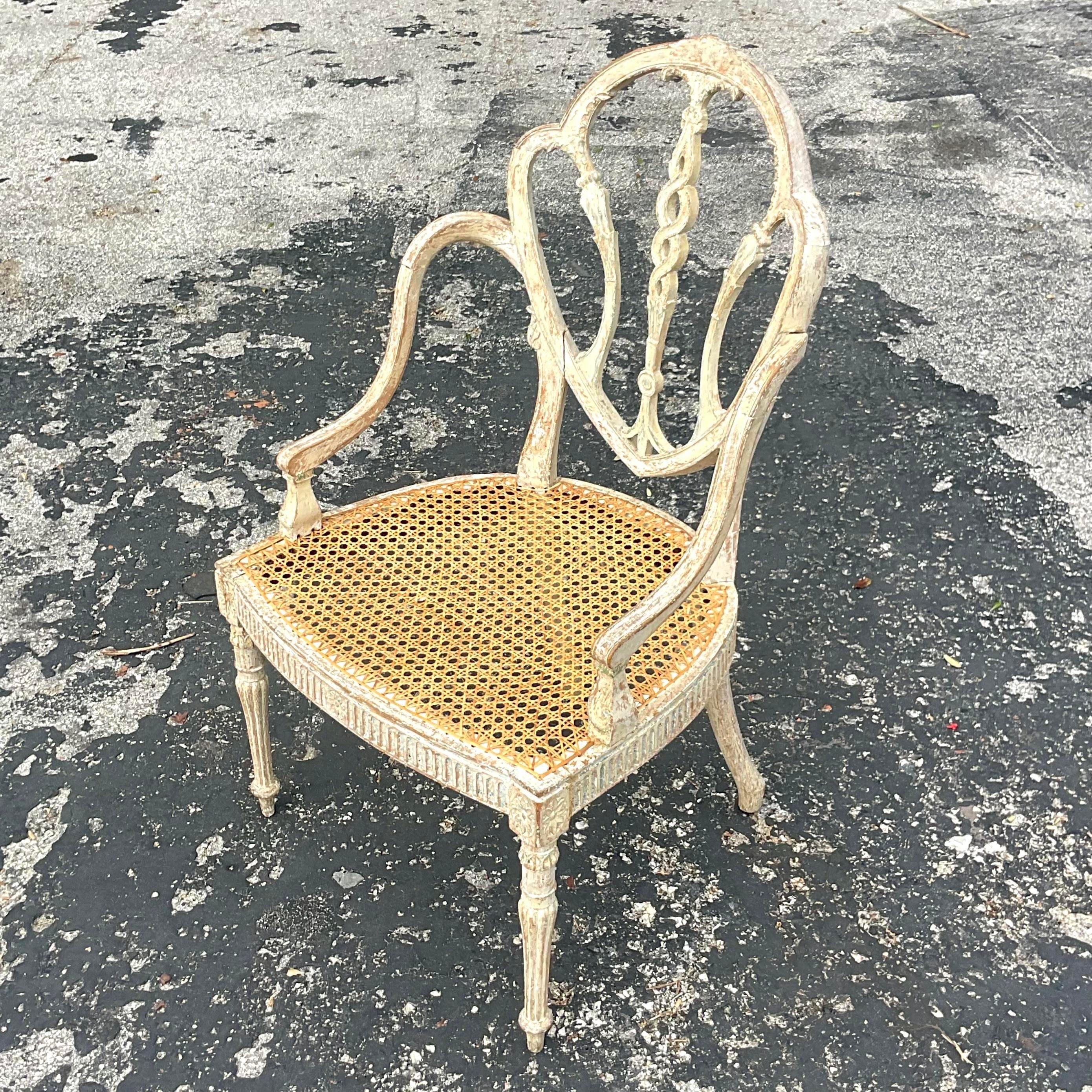A magnificent vintage Regency arm chair. A beautiful hand carved frame with an incredible patina from time. Hand woven cane seating looped into the frame. This chair is breathtaking, but it’s an older chair with a delicate seat. It will be the most