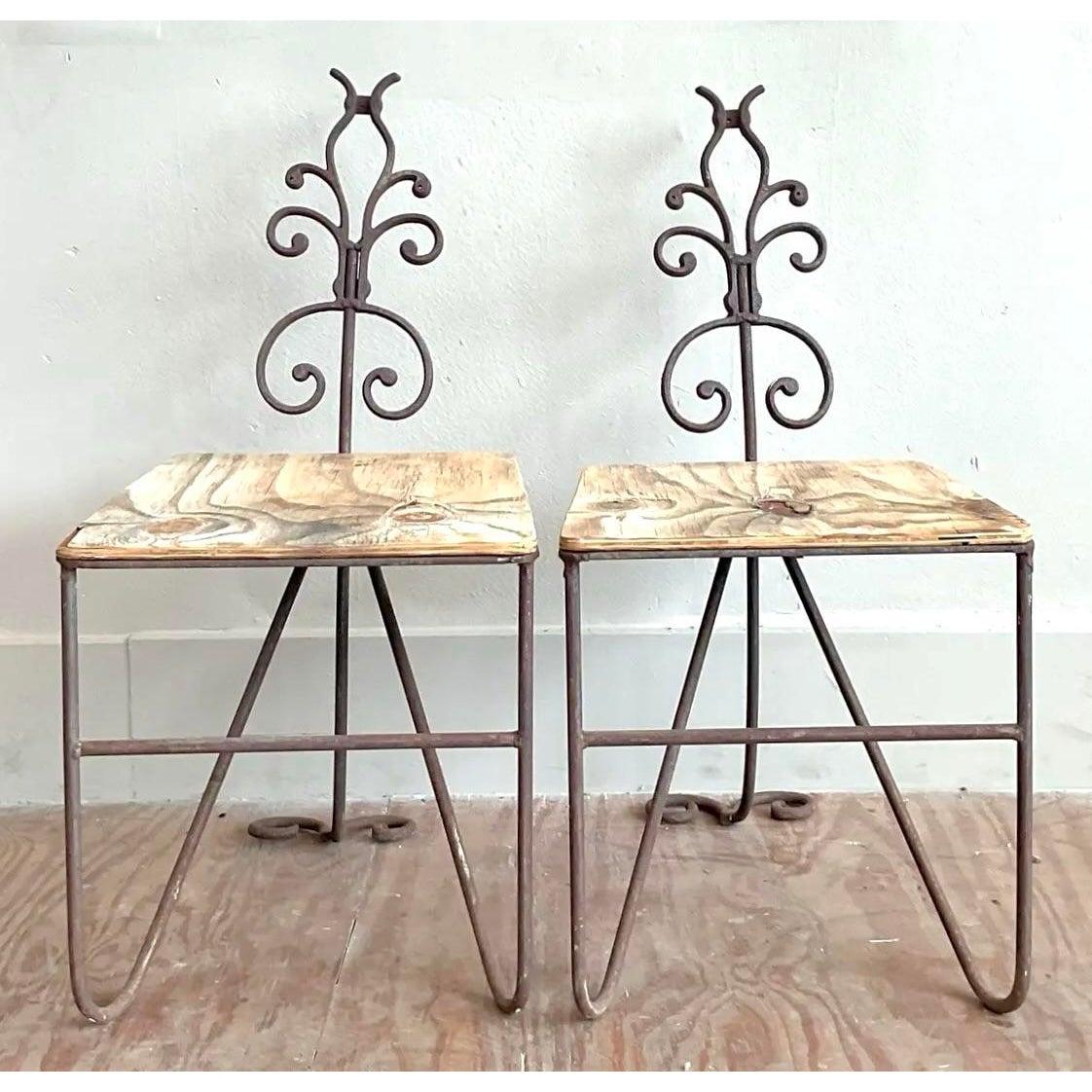 Presenting a captivating pair of vintage Hollywood Regency side chairs, exquisitely crafted from patinated wrought iron and topped with natural wood seats. These chairs embody a sophisticated blend of ornate detailing and rustic charm, featuring