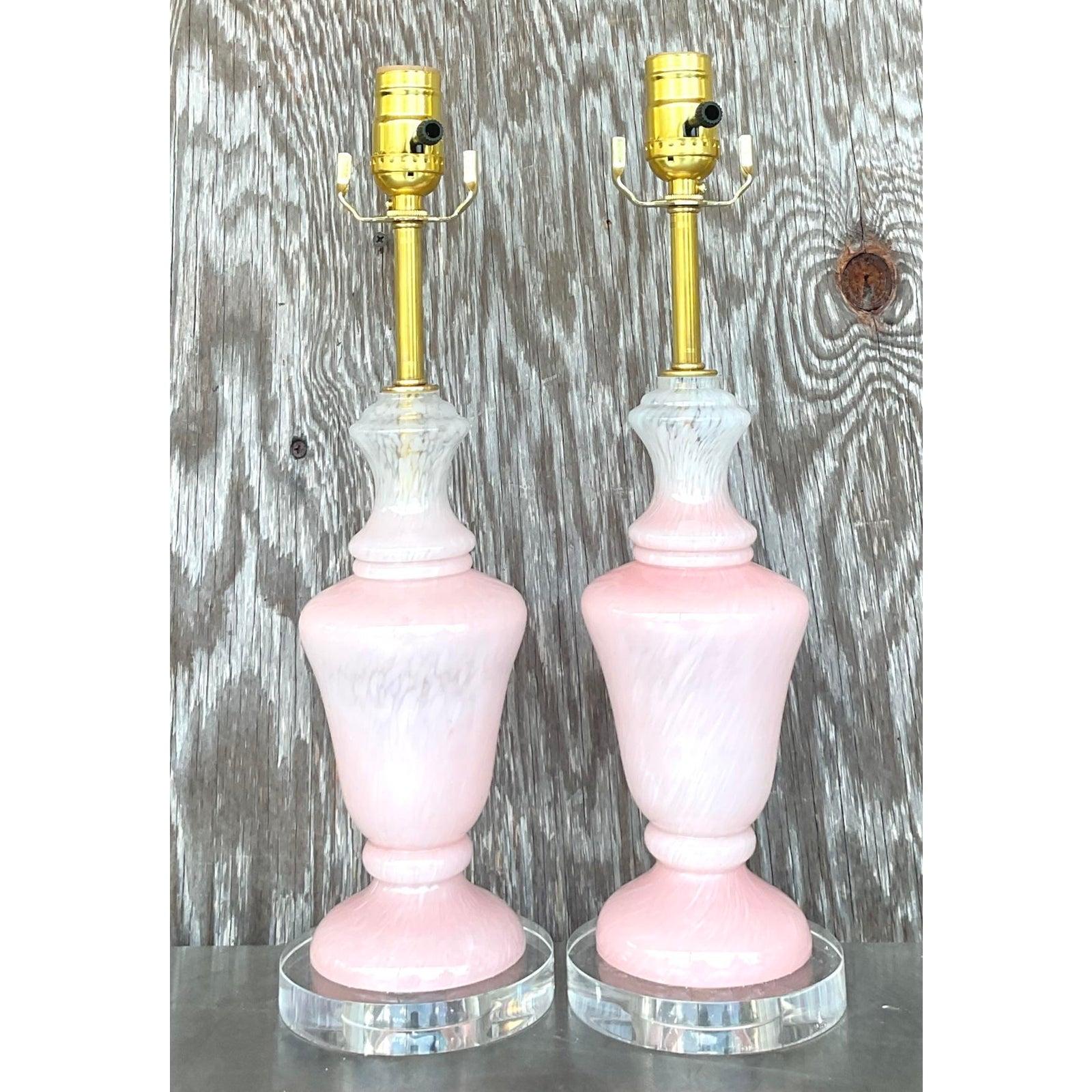 Add a touch of soft glamour and vintage sophistication with this exquisite pair of vintage pink glass table lamps inspired by Murano artistry. Featuring swirling hues of blush and white hand-blown glass atop clear Lucite bases, these lamps embody