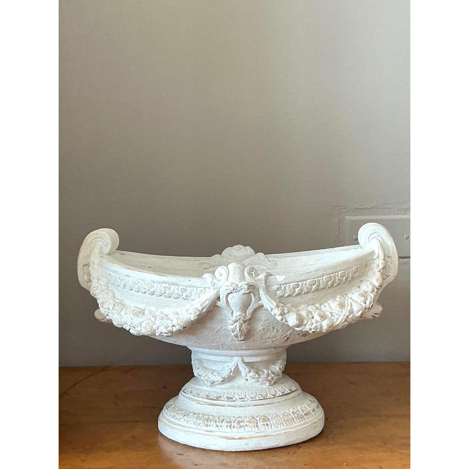 Trasmetti la grazia senza tempo di un maniero europeo con questa squisita ciotola con piedistallo in stile Regency vintage. Splendidamente realizzato in gesso, questo pezzo presenta una classica forma a urna impreziosita da intricati dettagli