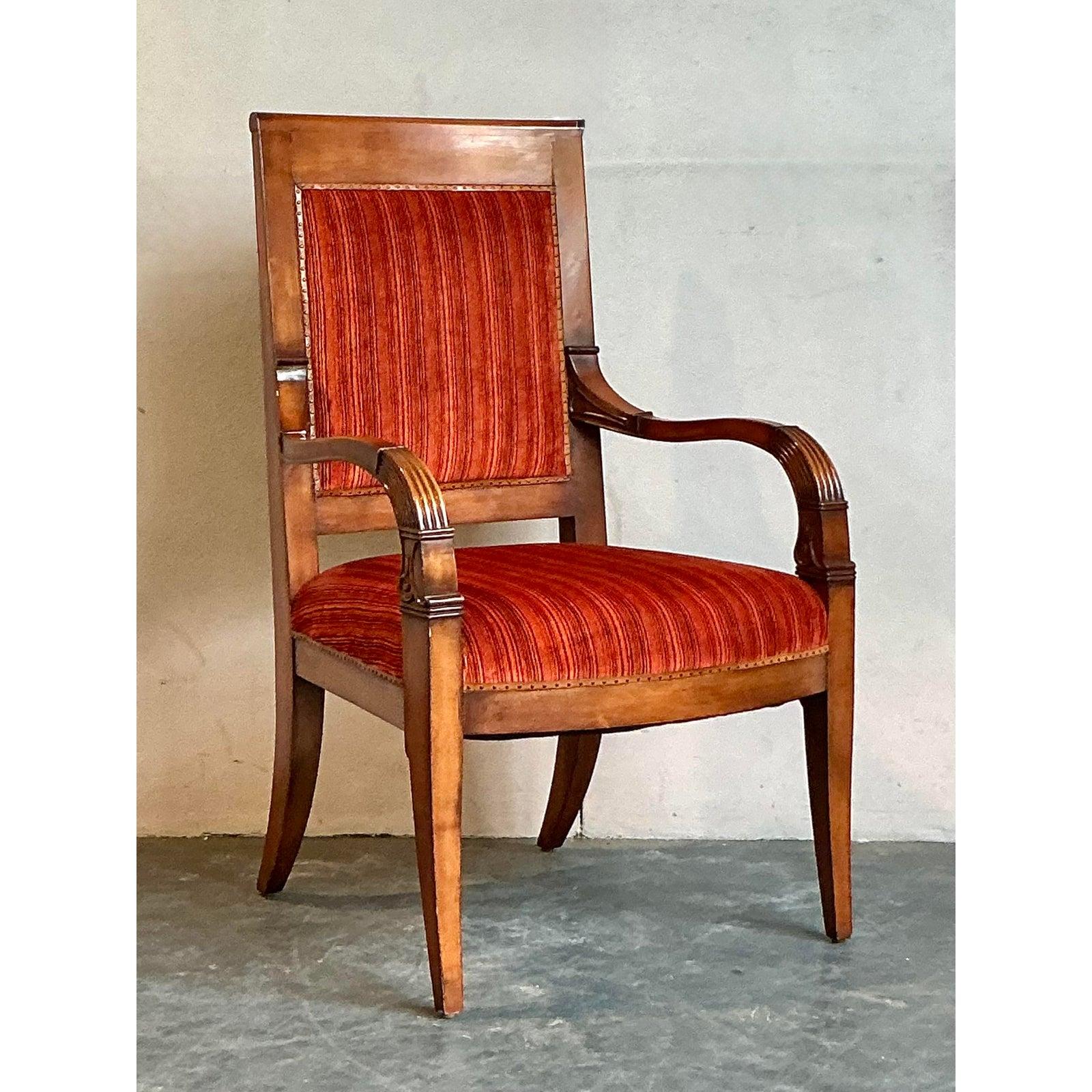 This elegant armchair is a superb example of the refined and formal design of the Regency and Empire periods. Its stately presence is defined by a tall, straight back and gracefully carved armrests, exuding a sense of timeless sophistication. The