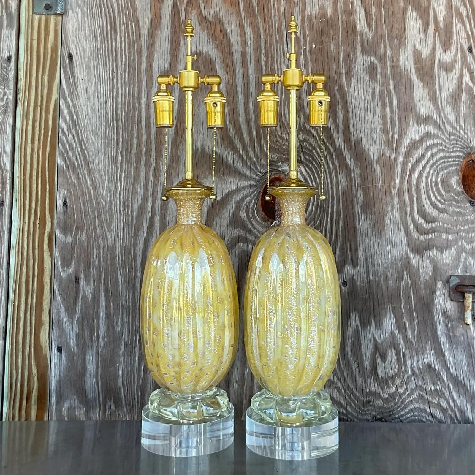 An exceptional pair of vintage Regency table lamps. Two stunning Murano glass lamps in a swirl design and rare champagne color. Fully restored with new wiring, polished brass double clusters and two inch lucite plinths. Just extraordinary. Acquired