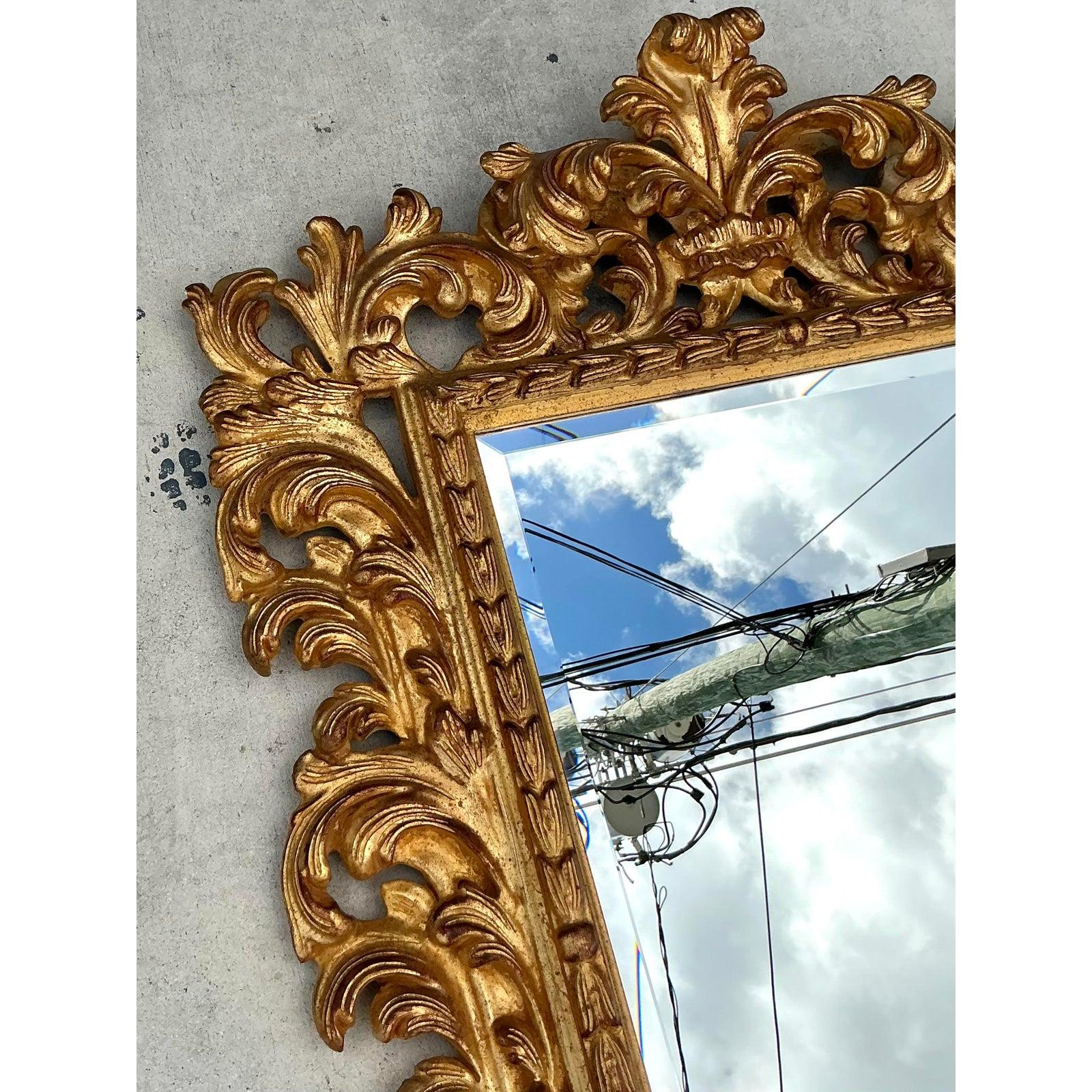 Fai una dichiarazione davvero glamour con questo squisito specchio d'epoca rococò dorato. Una celebrazione del design classico europeo, la sua cornice è un capolavoro di intaglio esuberante, con una sinfonia di foglie d'acanto a scorrimento che