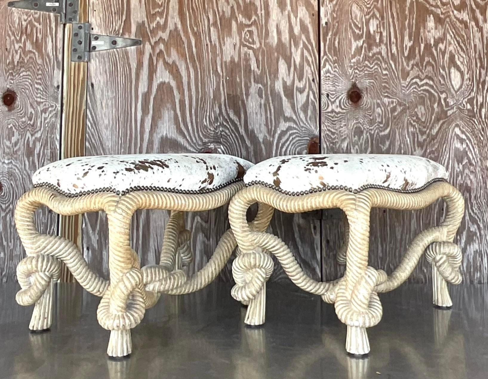 An extraordinary pair of vintage Regency low stools. The coveted rope and knot design with beautiful hand carved detail. A chic metallic leather hide upholstery. Acquired from a Palm Beach estate.