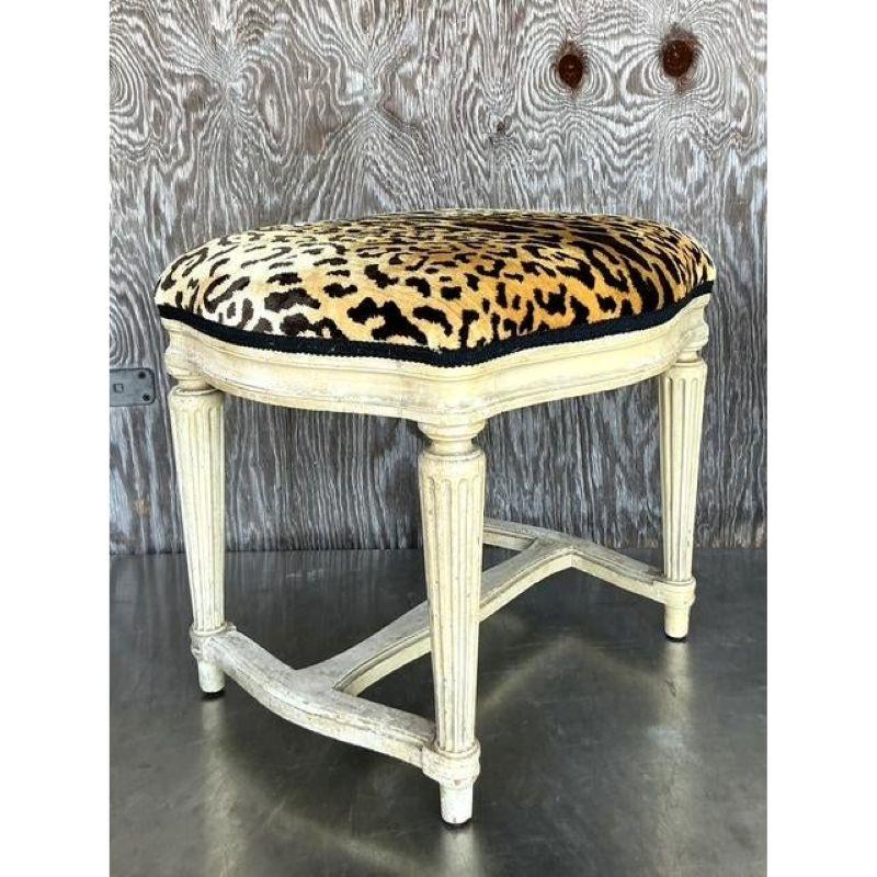 Ajoutez une touche audacieuse et glamour à votre espace avec cet exquis tabouret bas vintage de style Regency, doté d'un luxueux revêtement en velours léopard Scalamandré. Le cadre peint vieilli avec des pieds cannelés et une base de civière