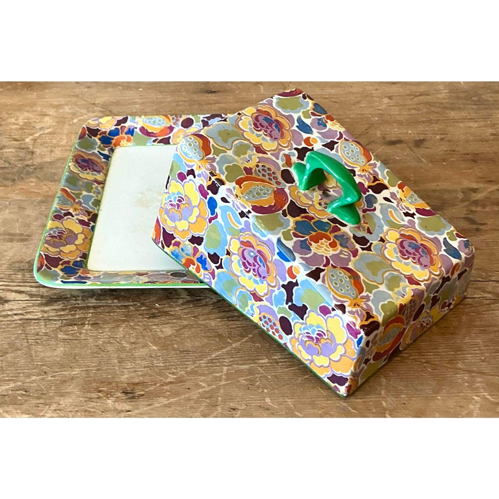 Diese entzückende Schale mit Deckel im Vintage-Stil ist ein Inbegriff des maximalistischen Designs, das durch kräftige Farben und überschwängliche Muster besticht. Mit seinem lebendigen, floralen Motiv in Lila-, Gelb-, Orange- und Limonengrüntönen