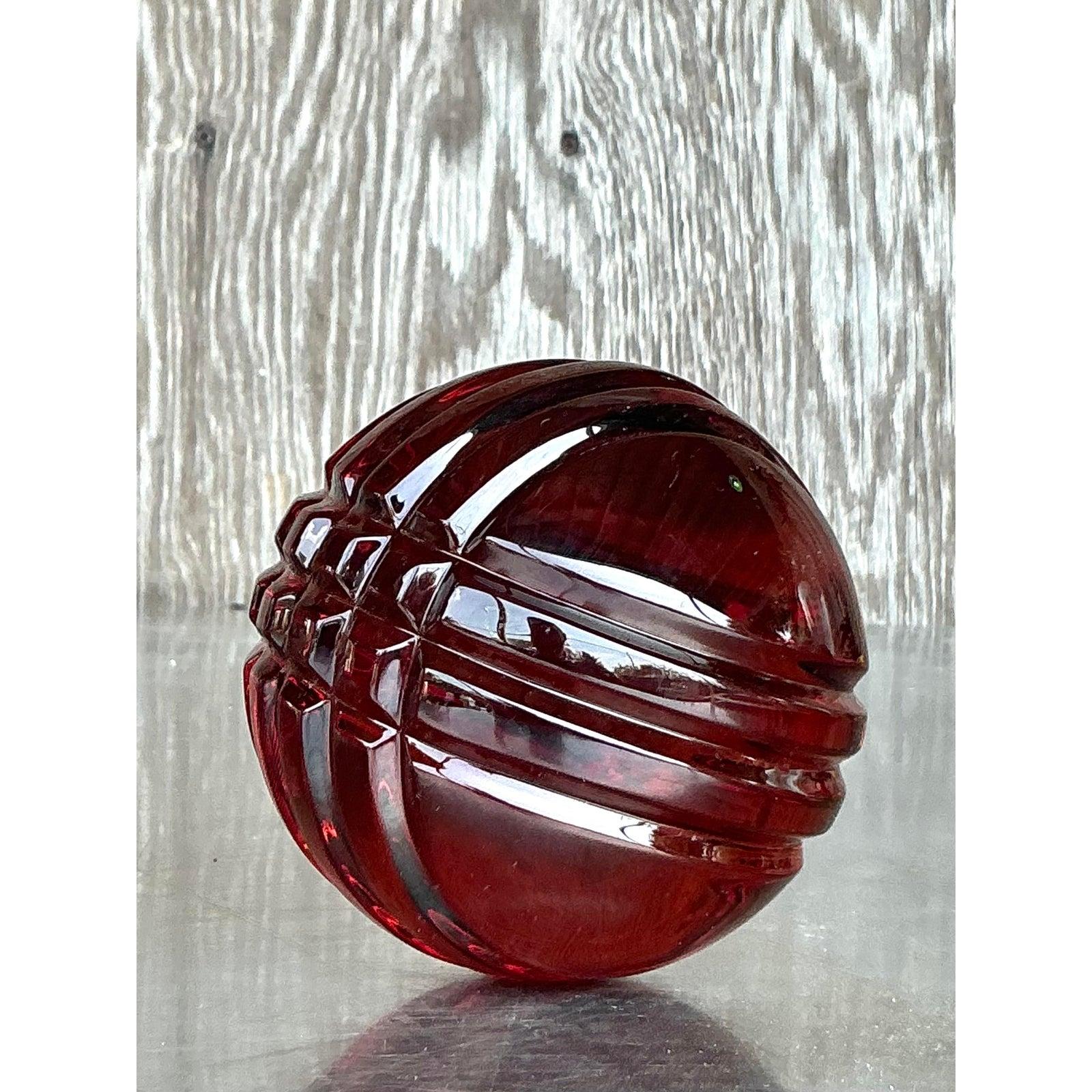 Eleganza audace per questa sfera in vetro massiccio Vintage Regency. Ricca di profondi toni rubino e sapientemente tagliata con suggestive fasce geometriche, questa sfera in vetro massiccio cattura l'opulenza del design di metà secolo con un tocco
