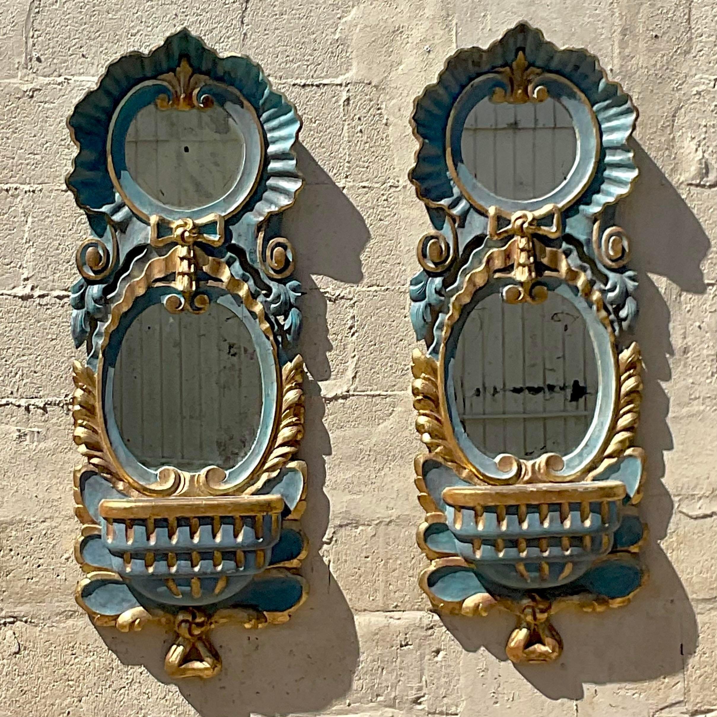 An exceptional pair of vintage Regency mirrors. Made by the Iconic Chapman group. Made in Spain with beautiful gilt tipped edges over a cool blue. Small shelf for your treasured objet, or just your keys! You decide! Acquired from a Palm a each