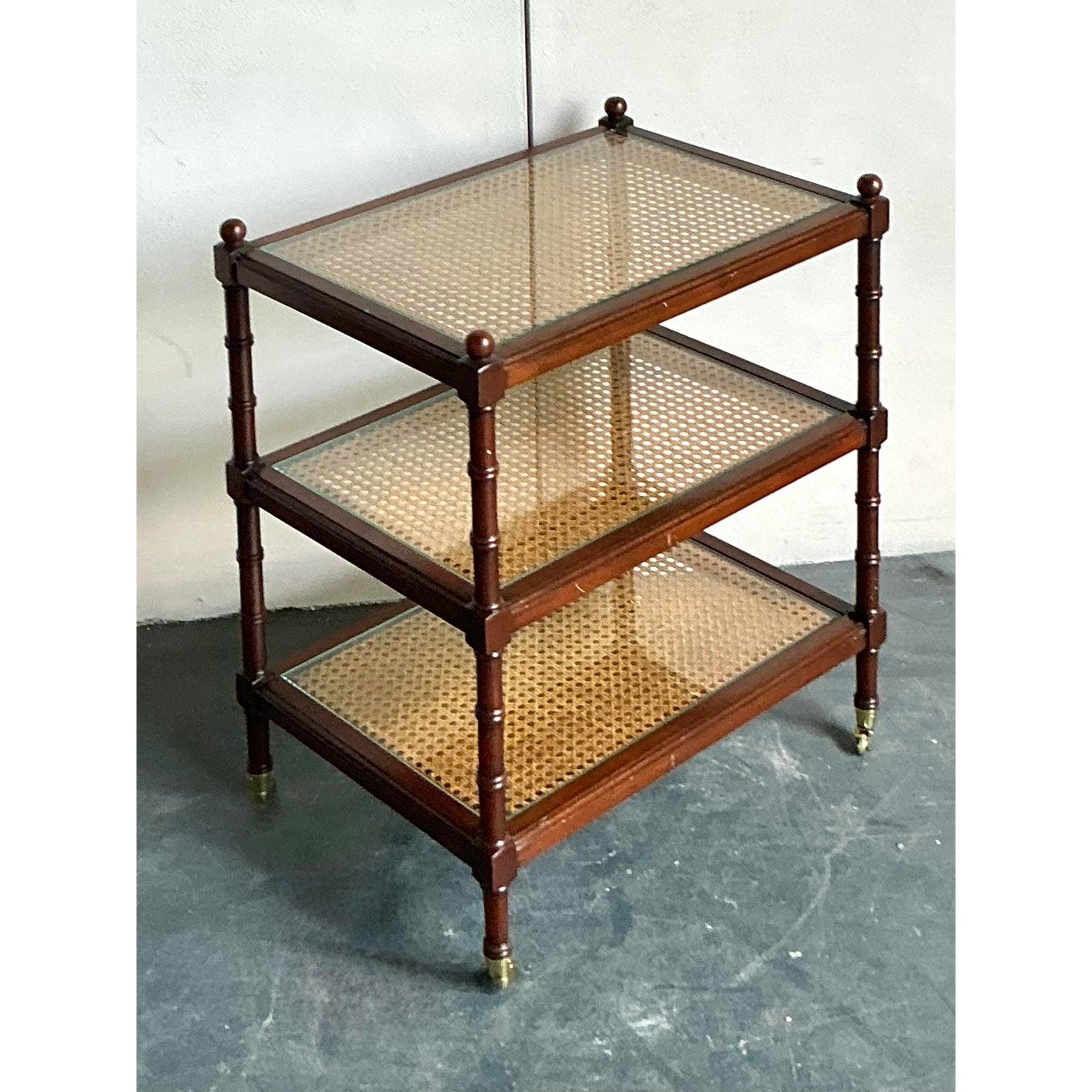 Entdecken Sie den zeitlosen Charme der Chinoiserie mit dieser eleganten dreistöckigen Etagere im Vintage-Stil. Der meisterhaft aus Holz gefertigte Rahmen mit seiner warmen Oberfläche ist kunstvoll gedrechselt und erinnert an Bambushalme, ein