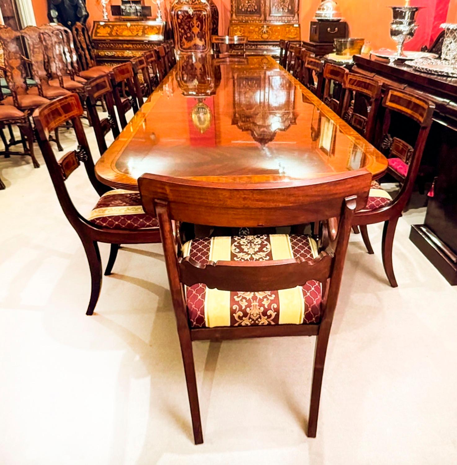 This is a beautiful Regency style dining table complete with the matching set of eighteen chairs, dating from the last quarter of the 20th century.

The table is made of flame mahogany with superb satinwood crossbanded decoration.. It will seat