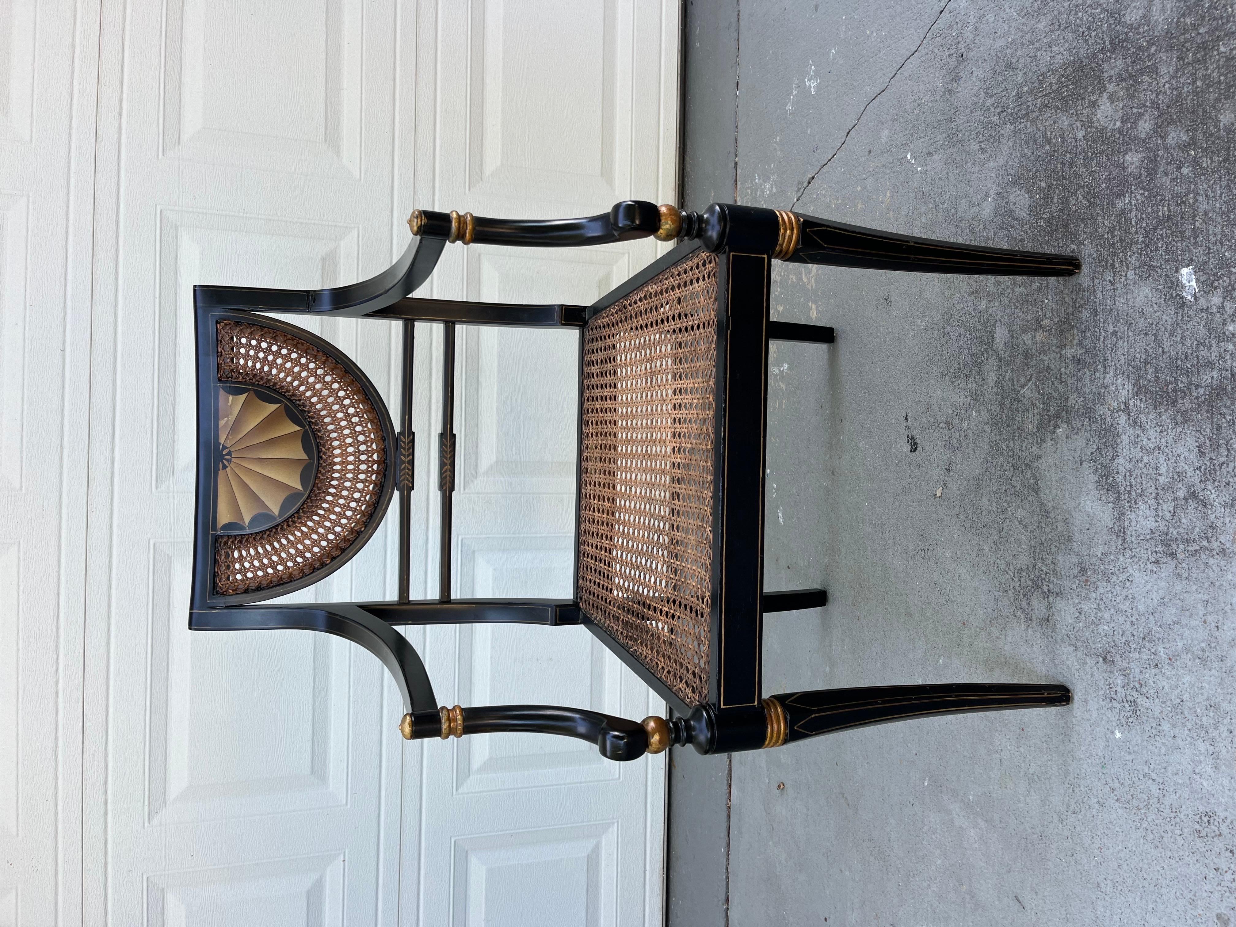 Vintage Regency Style Ebonized Armchair with Cane Seat

20th century Regency style armchair from the cabinet maker Trouvailles, Watertown Massachusetts. It is black lacquered with gold painted accents. Seat and back are caned and decorated with hand