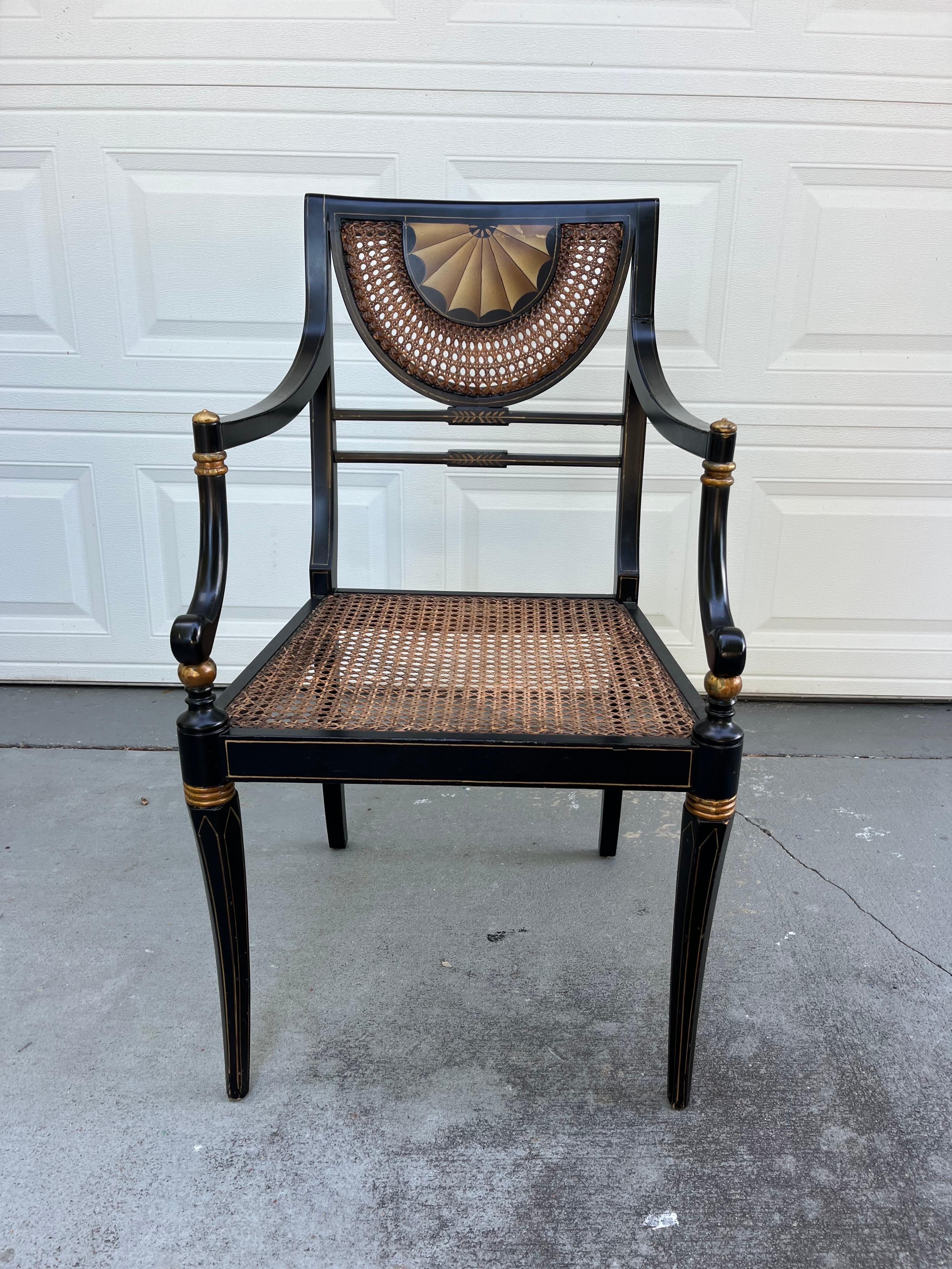 Vintage Regency Style Ebonized Armchair with Cane Seat

20th century Regency style armchair from the cabinet maker Trouvailles, Watertown Massachusetts. It is black lacquered with gold painted accents. Seat and back are caned and decorated with hand