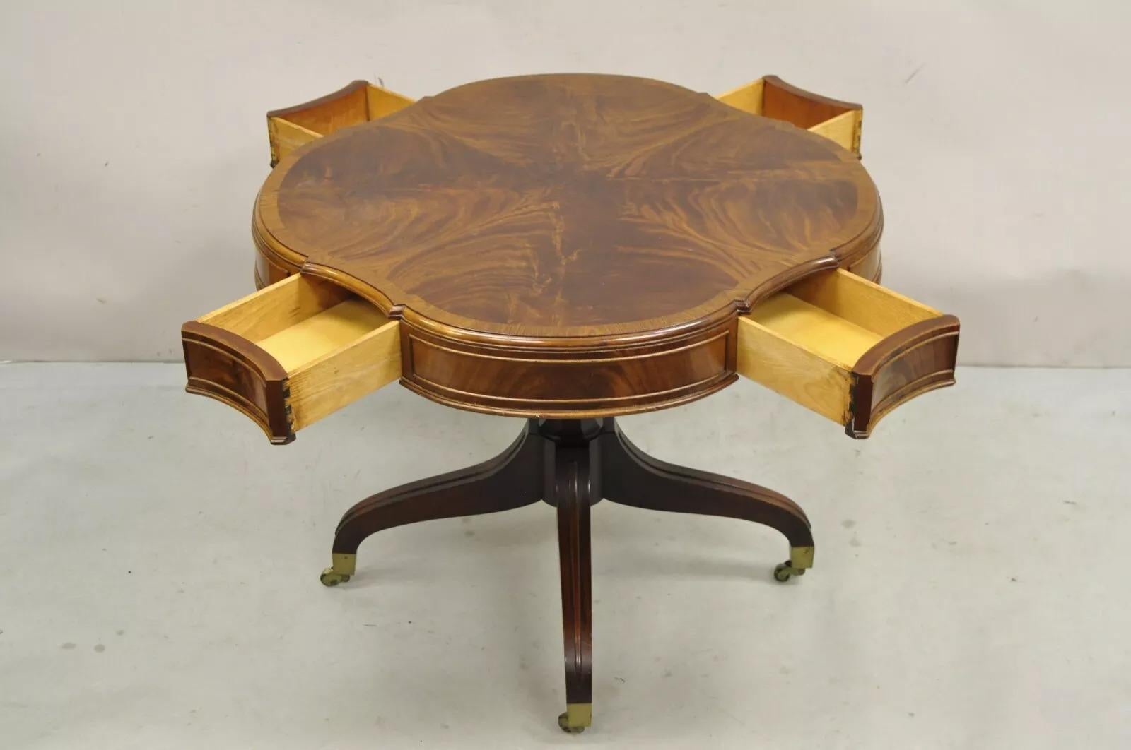 Vintage Regency Style Flamed Mahogany Four Drawer Pedestal Base Lamp Table. Item features 4 dovetailed drawers, brass rolling casters, and flamed mahogany wood grain. Circa Early 20th Century. Measurements: 25.5