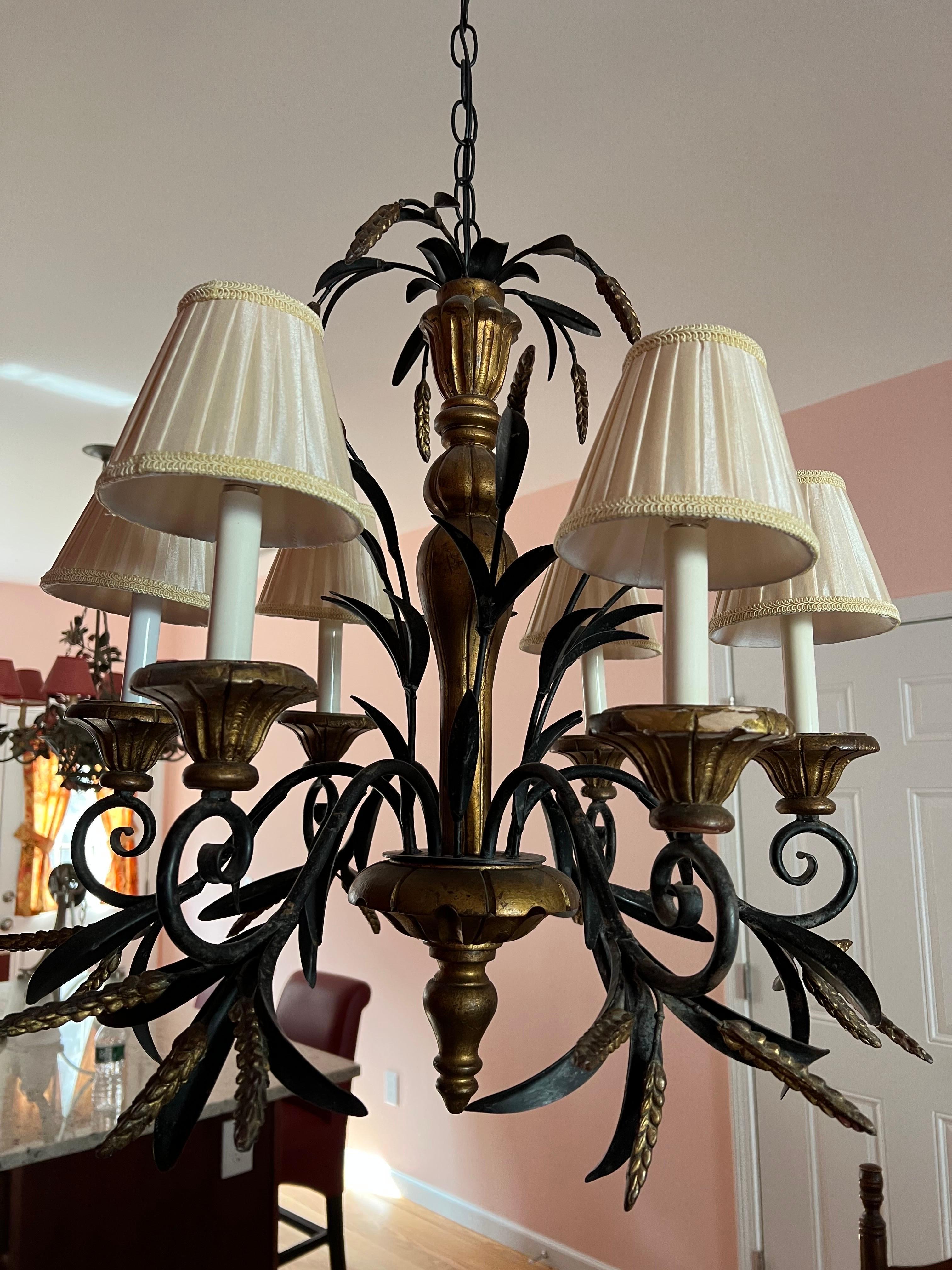  Tole Wheat Sheaf Chandelier in the style of Currey and Company. Painted black tole and wooden gilt design make up this six armed beauty. Soft ivory cloth shades. Elegant and timeless in design. Glamourous Regency Design. This item can most likely