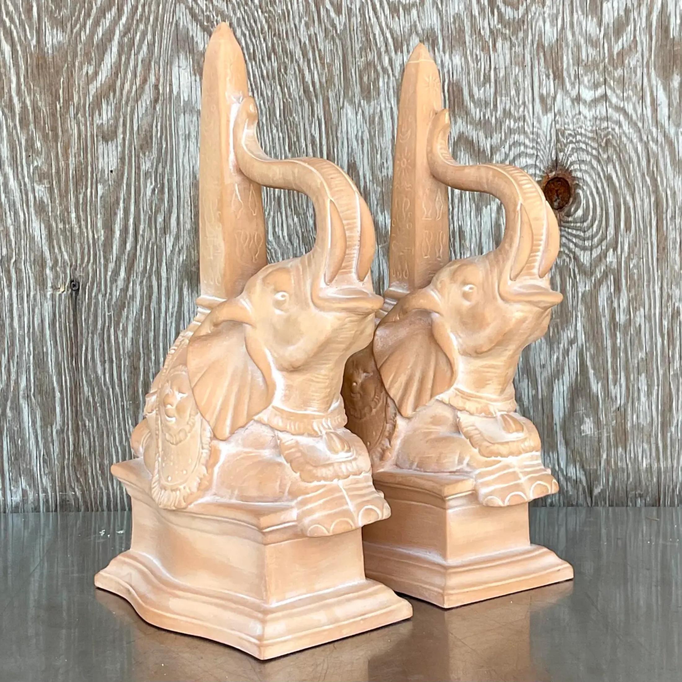 A handsome pair of vintage Regency obelisks. A cast terracotta with a cerused finish. Happy elephants with their trunks up for good luck. Acquired from a Palm Beach estate