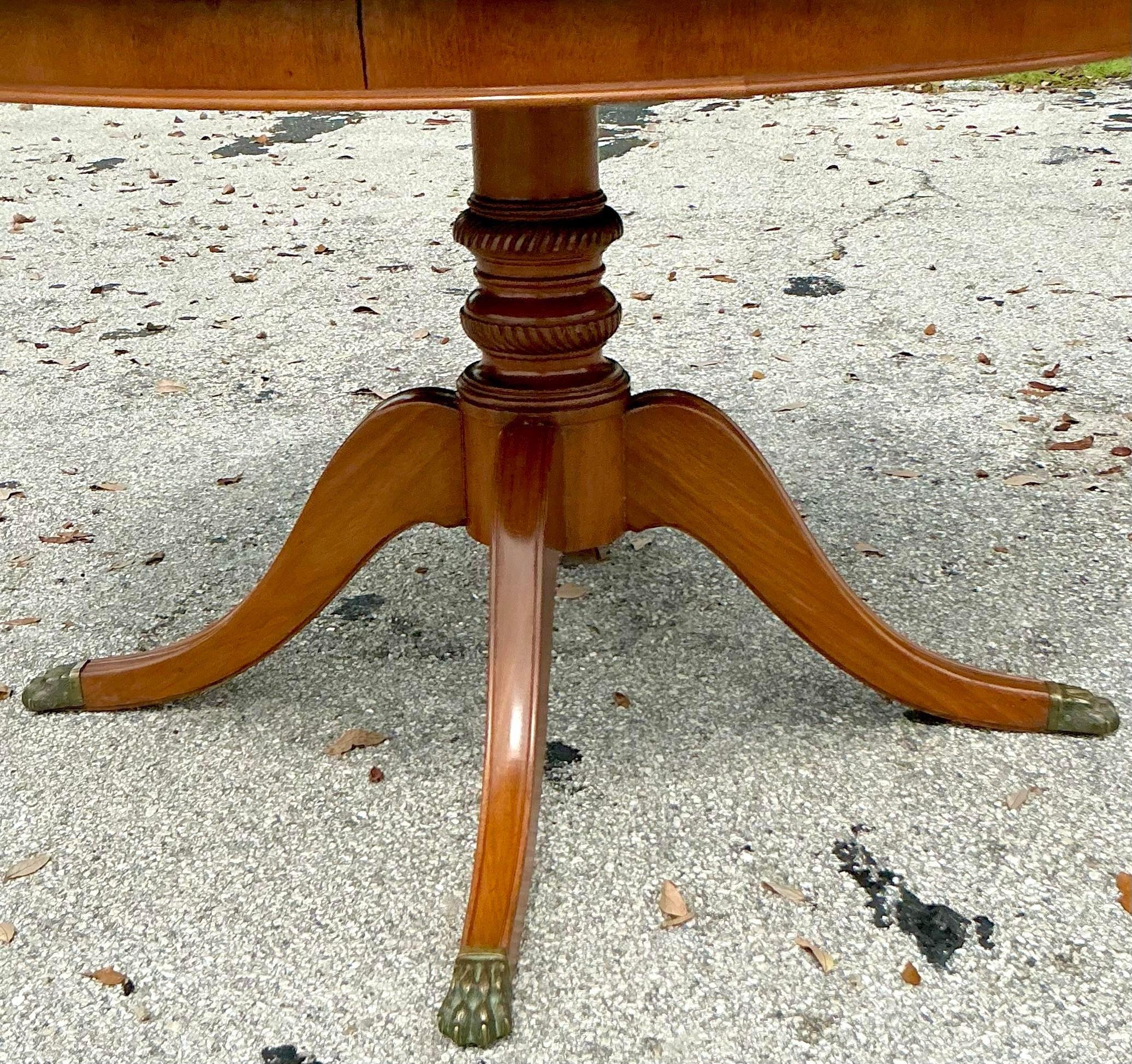 Explore the sophistication of the 'Vintage Regency Three-Legged Marquis Center Hall Table', a hallmark of refined elegance and classical design. With its distinctive three-legged silhouette and marquetry details, this table exudes timeless charm and