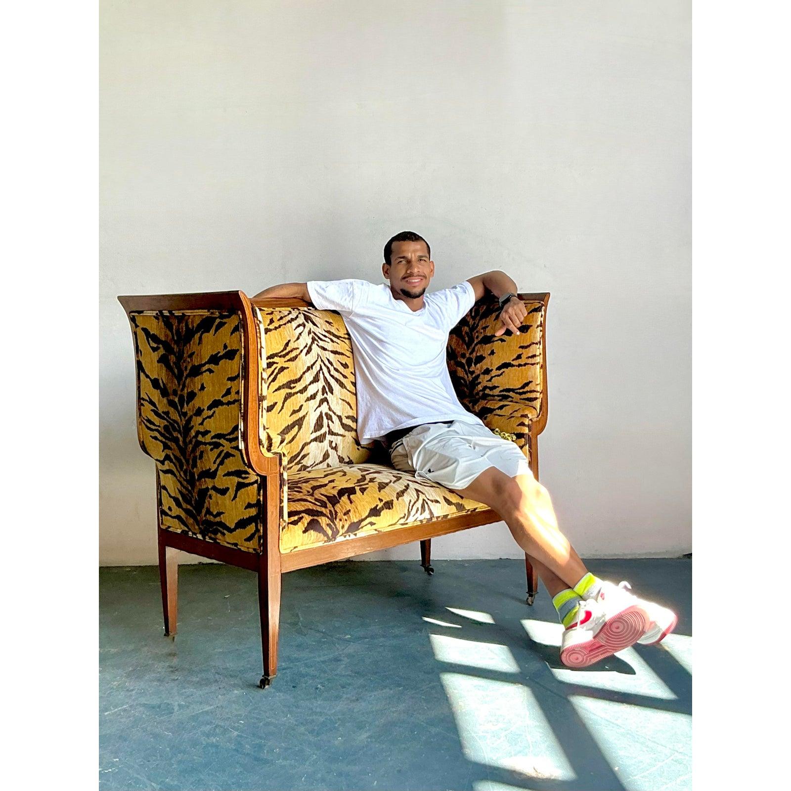This exquisite vintage settee embodies the luxurious allure of Hollywood Regency design, offering a bold statement piece for any sophisticated interior. Upholstered in a plush velvet fabric featuring a striking tiger stripe pattern, it exudes