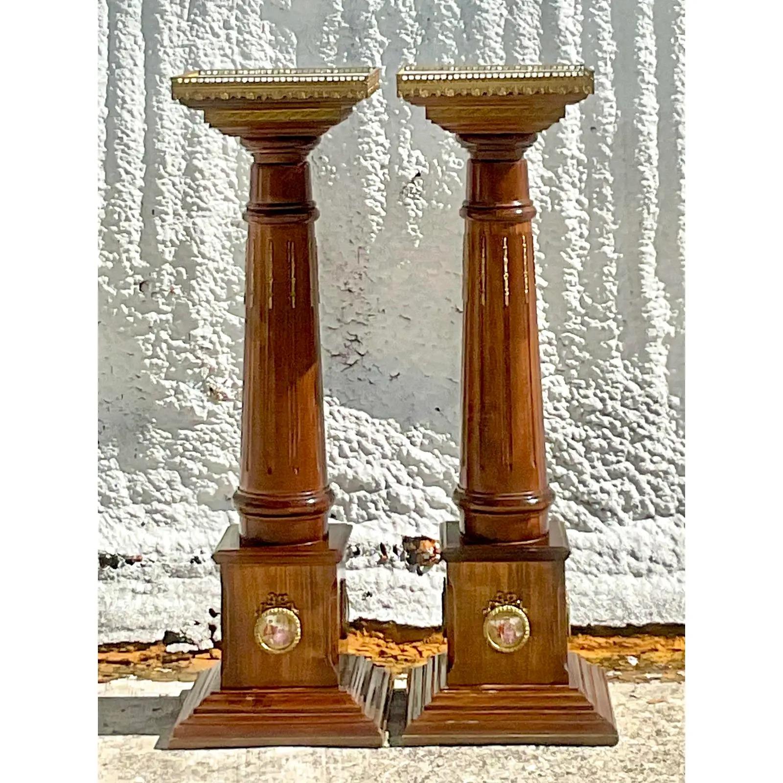 An incredible pair of vintage Regency pedestals. Tall and slender carved wood with the most gorgeous hand painted Wedgwood China cameos around the bottom of the pedestals. Inset marble tops with brass railing. Acquired from a Palm Beach estate.