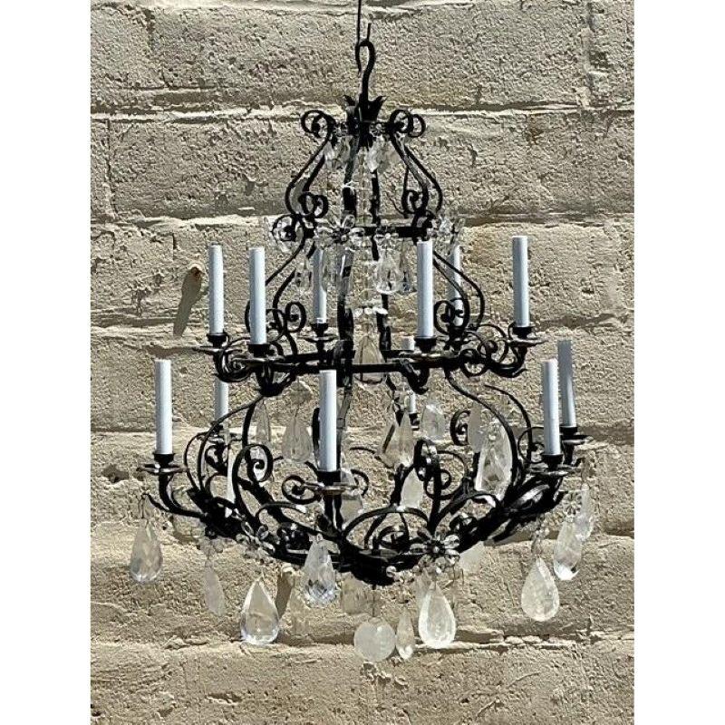 Illumina il tuo spazio con l'eleganza senza tempo e la bellezza scintillante di questo lampadario vintage, caratterizzato da un design classico di ispirazione Regency. Realizzata in ferro battuto, la cornice ornata crea un contrasto drammatico con i