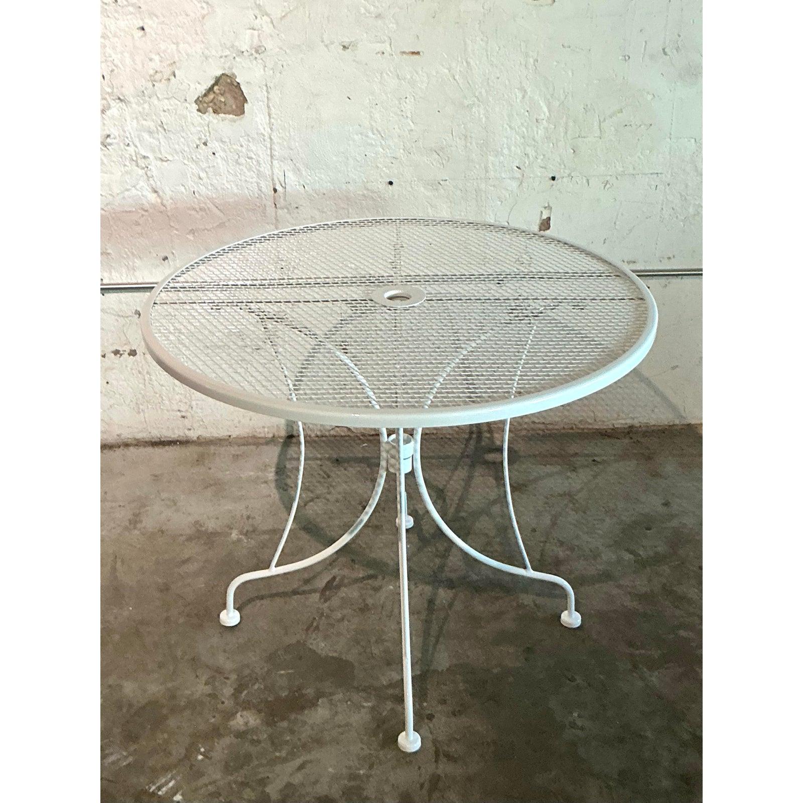 Embrace the timeless charm of al fresco dining with this delightful vintage wrought iron table. Featuring a classic diamond-pattern mesh top and gracefully scrolled legs, this piece exudes the romantic spirit of a European bistro or a serene garden