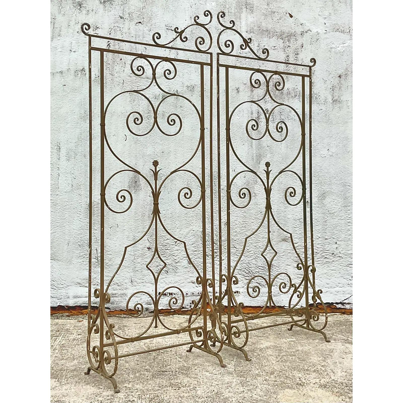 Fabulous vintage Regency wrought iron gate screen. Beautiful pair of free standing panels in a pale gold. Perfect as a room divider, garden trellis or even chic as a store window. Acquired from a Palm Beach estate.