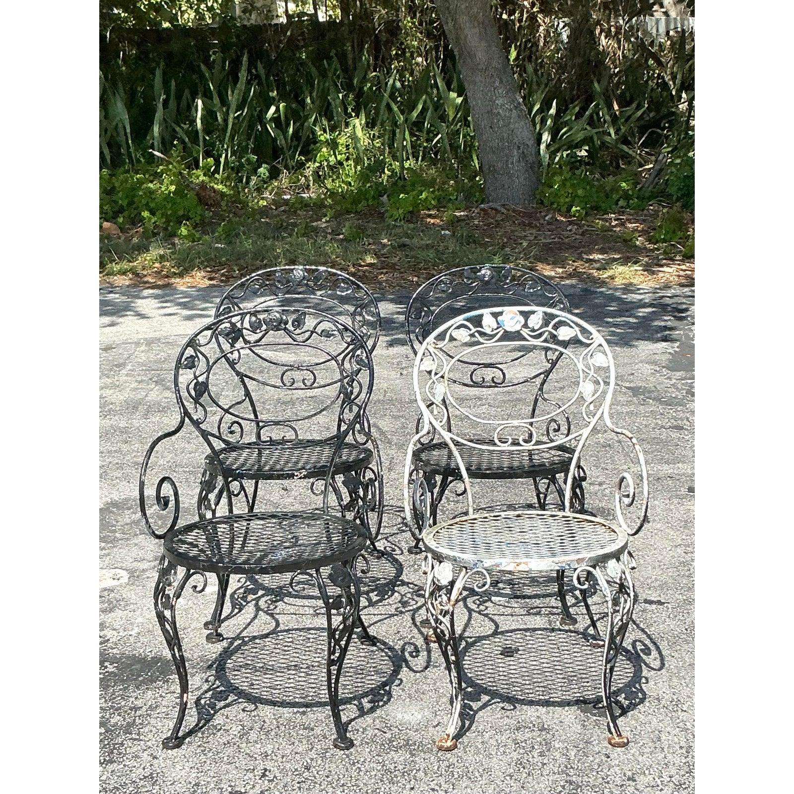 Transform your outdoor space with this elegant Vintage Regency Wrought Iron Outdoor Dining Set, a five-piece ensemble that blends timeless sophistication with durable craftsmanship. Dating back to the 1960s, the set features a round glass-top table