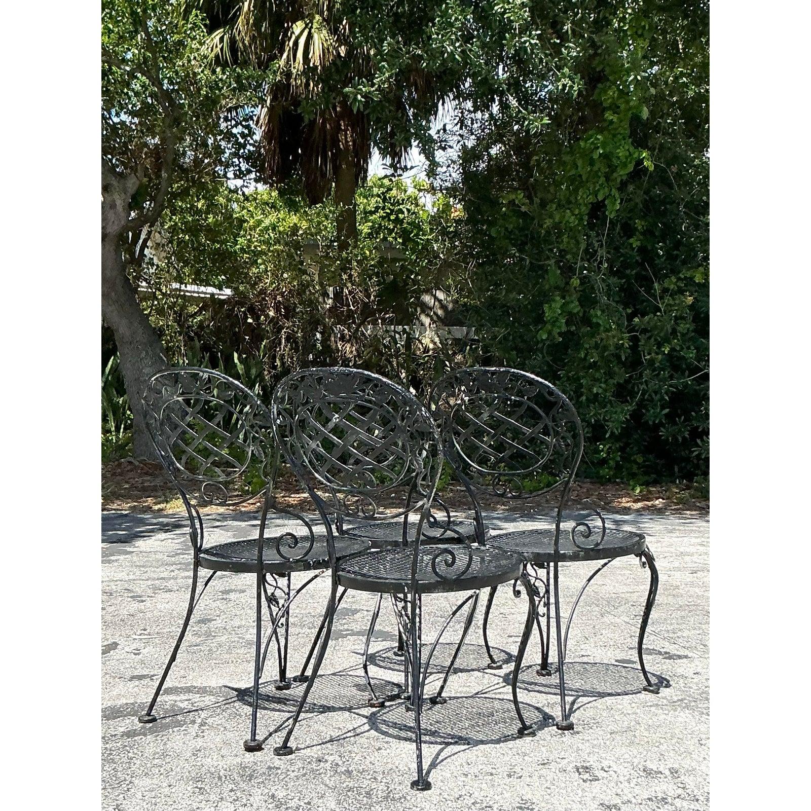 Enhance your outdoor oasis with this enchanting Vintage Regency Wrought Iron Grapevine Outdoor Dining Set, a five-piece collection that exudes romantic elegance and historical charm. Crafted in the 1970s, the set features a rectangular glass-top