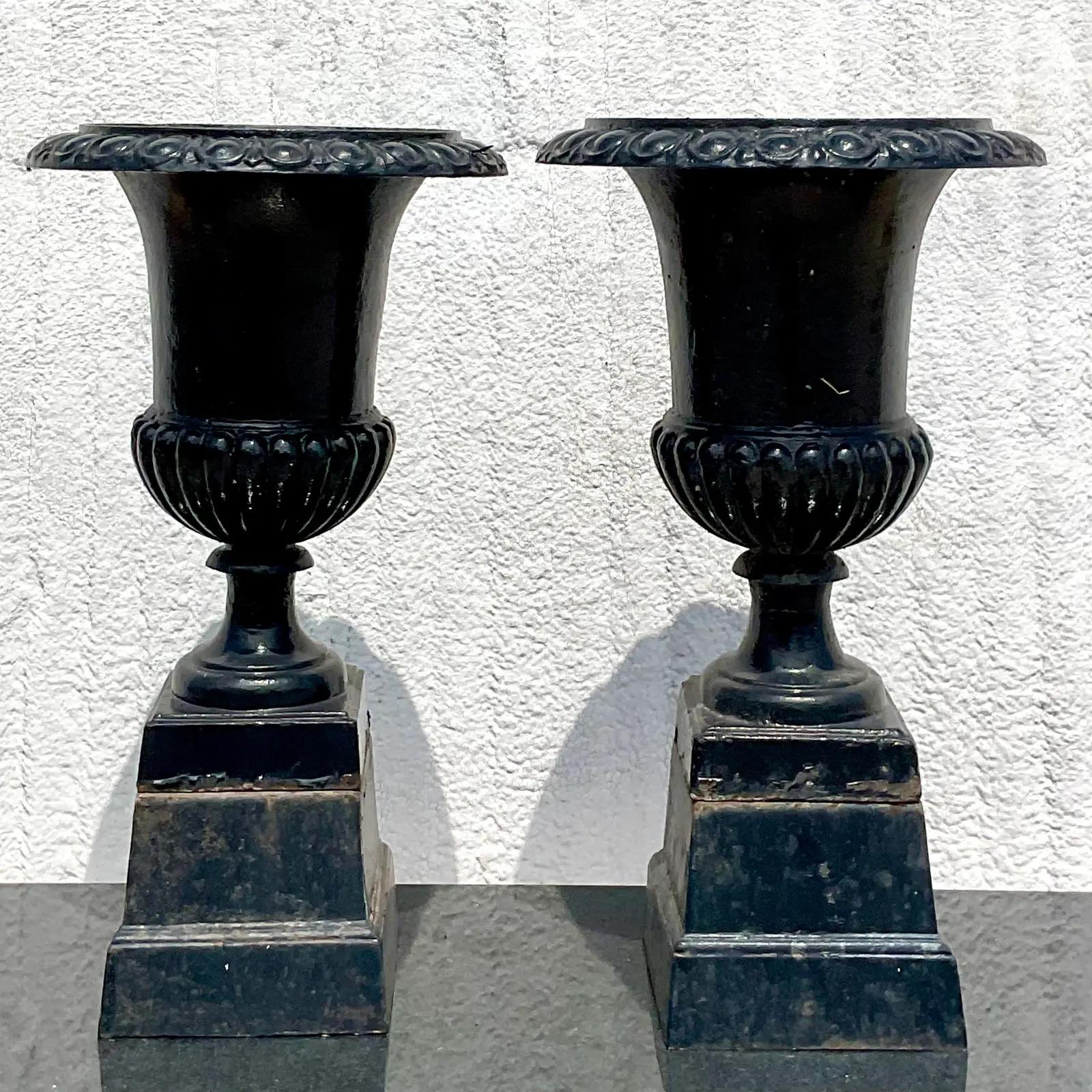 Fantastic pair of vintage wrought iron urns. A chic pair painted a glossy black. Perfect in the garden or on either side of your front door. Gorgeous indoors also. Acquired from a Palm Beach estate.