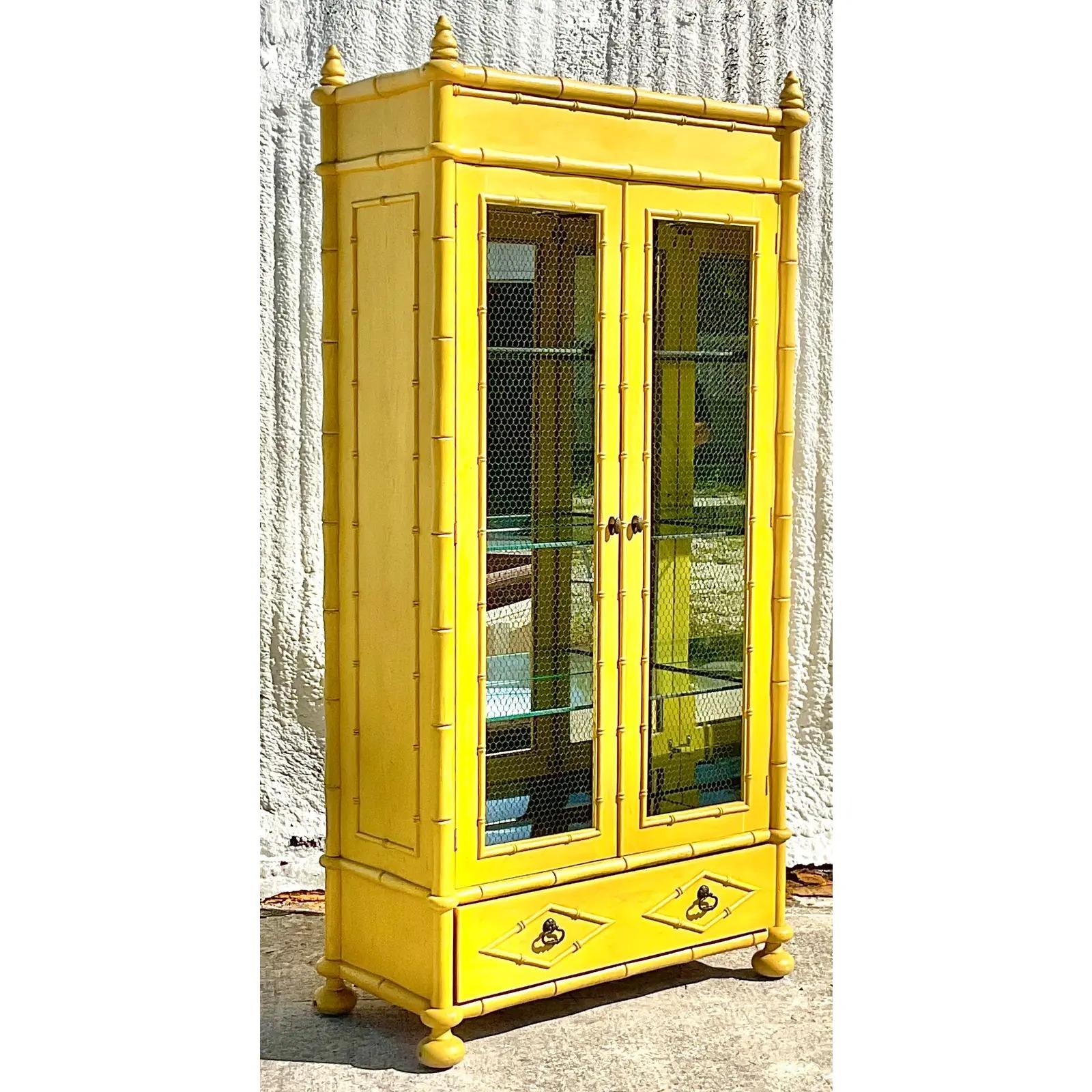 A fantastic vintage Regency mirrored display cabinet. A stunning piece of furniture made by the Youngsville Star Manufacturing group. A custom piece with a fully mirrored interior and glass shelving. Brilliant yellow color with wire inset door