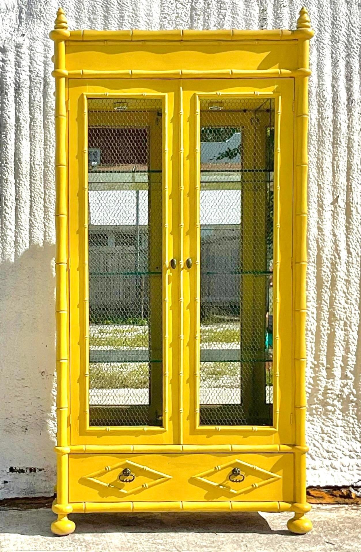 A fantastic vintage Regency mirrored display cabinet. A stunning piece of furniture made by the Youngsville Star Manufacturing group. A custom piece with a fully mirrored interior and glass shelving. Brilliant yellow color with wire inset door