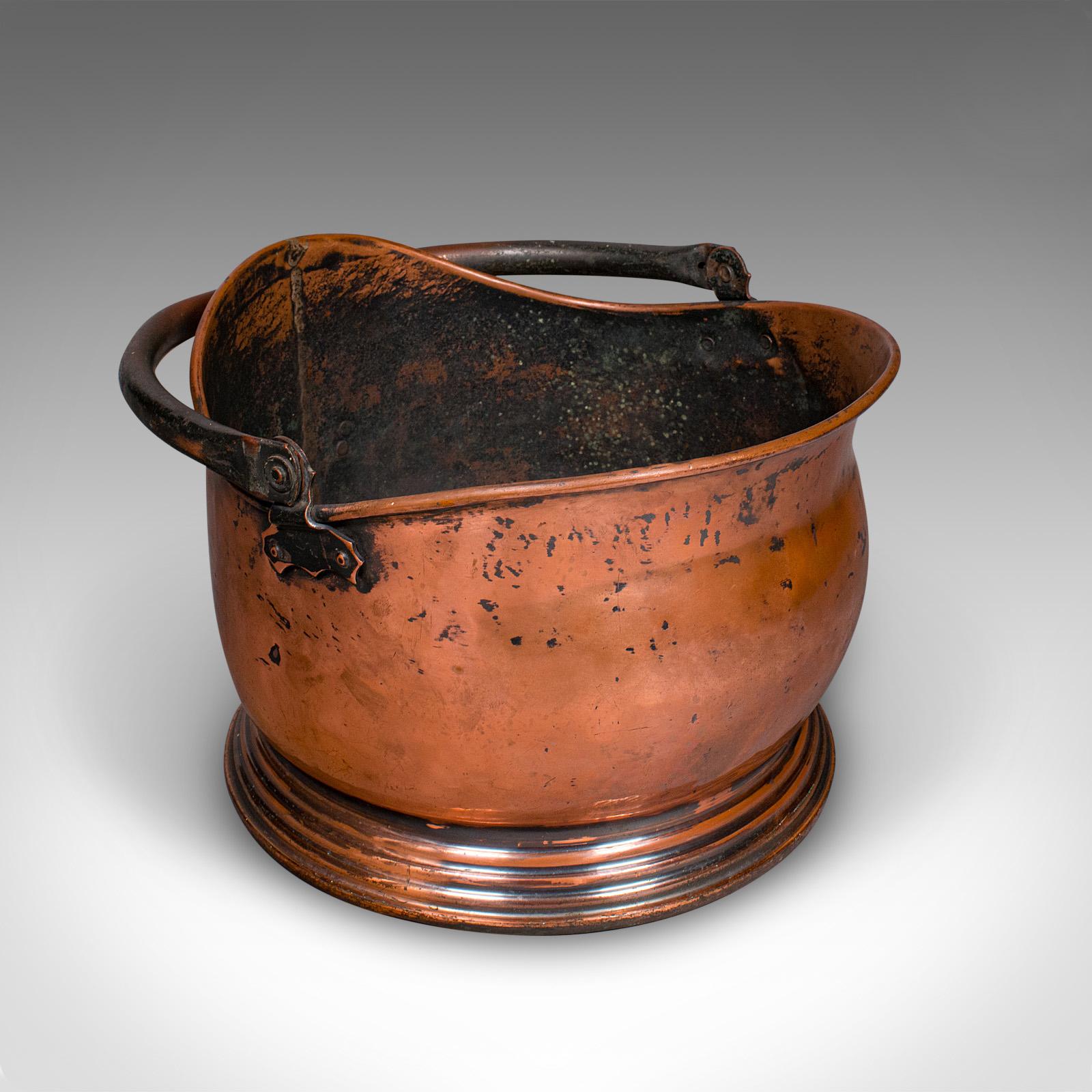 This is a vintage regimental mess coal bucket. An English, copper fireside helmet scuttle bearing the military broad arrow, dating to the mid 20th century, circa 1960. A charming and practical fireside piece with timeless military and domestic