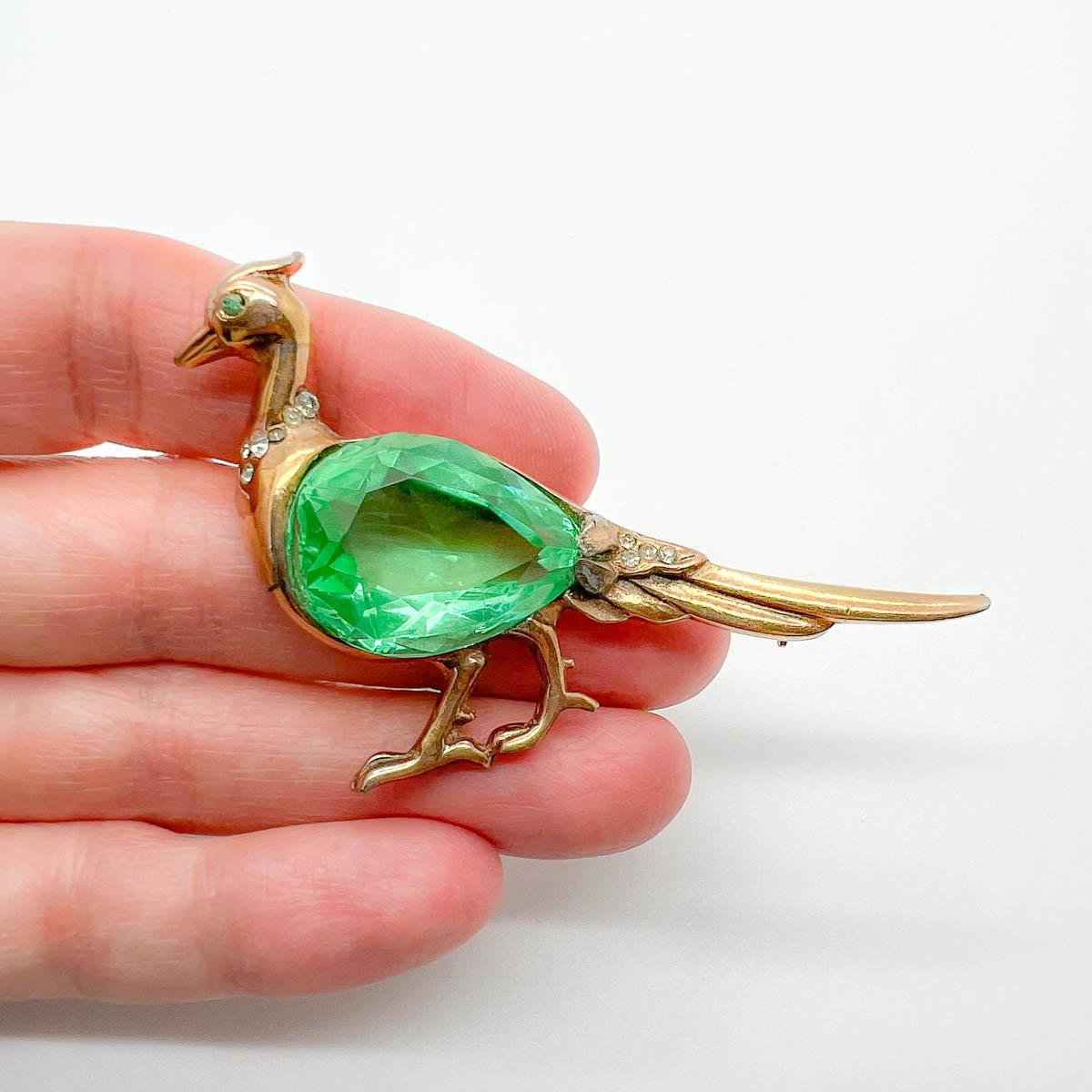 A charming Vintage Reja Peacock Brooch. Golden metalwork surrounds a huge green fancy cut crystal depicting the Peacock's body. A rare and whimsical treasure from costume jewel house Reja in the 1940s. Totally charming lapel decoration.
Reja was