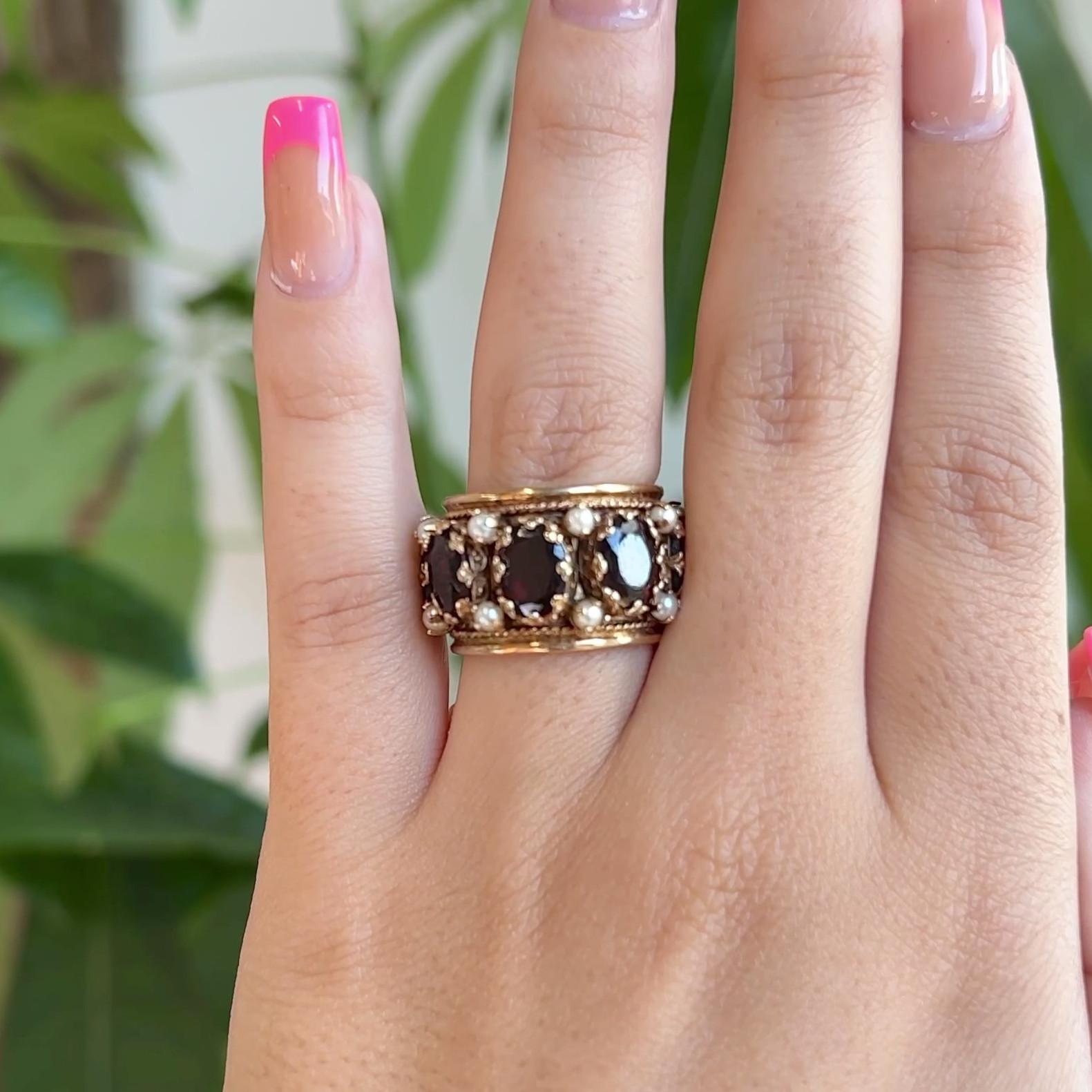 One Vintage Renaissance Inspired Garnet Pearl Yellow Gold Thick Band. Featuring eight oval mixed cut garnets with a total weight of approximately 10.00 carats. Accented by 16 pearls. Crafted in yellow gold with purity marks. Engraving inside band