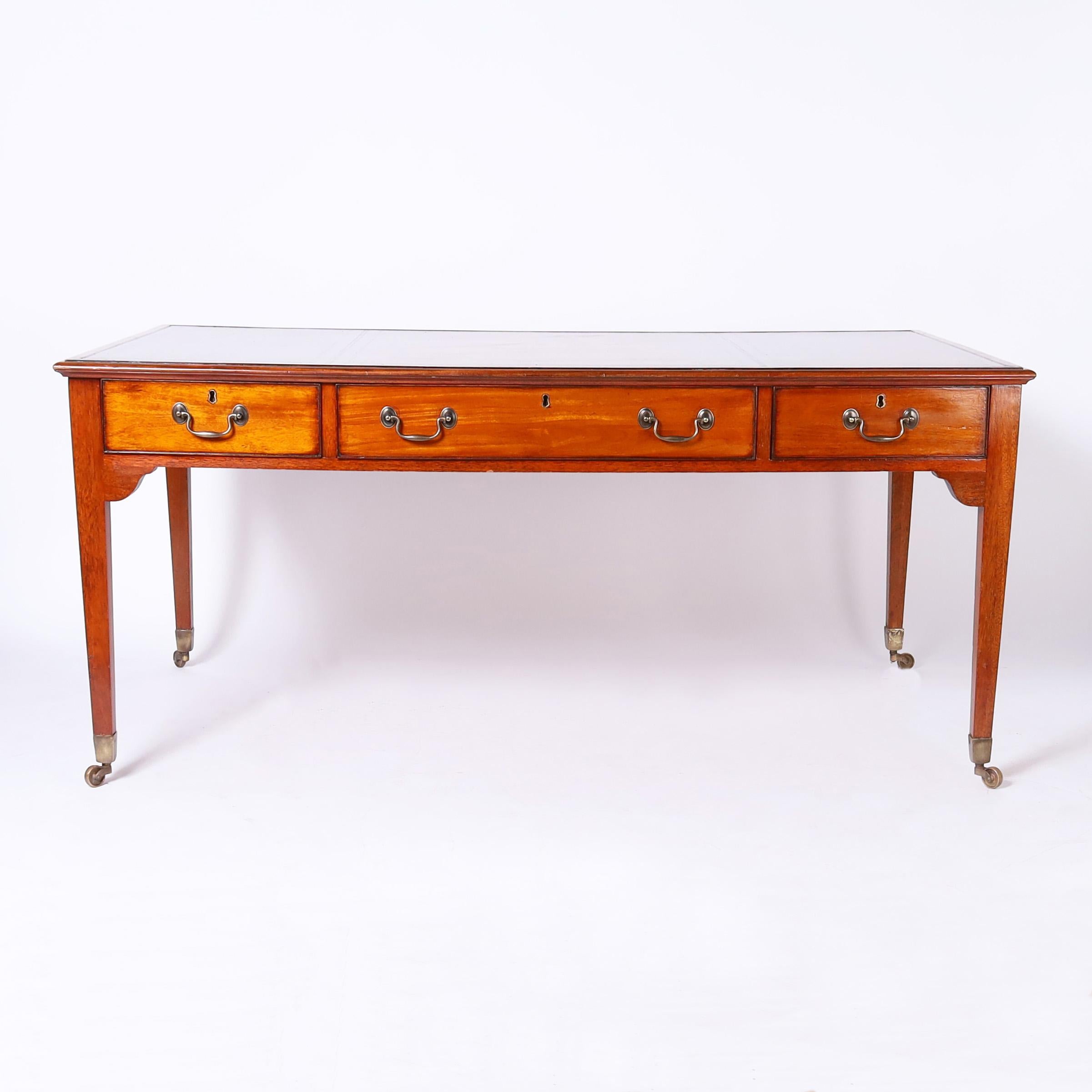 Handsome copy of Winston Churchill's George III style partners desk crafted in mahogany with a tooled leather top on a case with three drawers on either side supported by square tapered legs with brass casters. The original desk can be seen at the