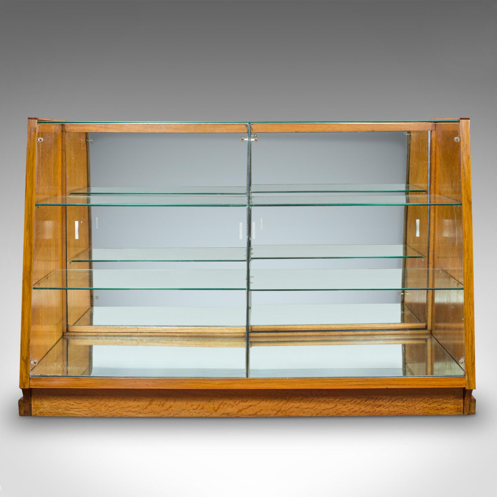 This is a vintage retail display cabinet. An English, oak and glass haberdashery or shop showcase, dating to the Art Deco period, circa 1930.

Pleasingly shaped, bright display cabinet
Displaying a desirable aged patina
Oak veneer shows rich