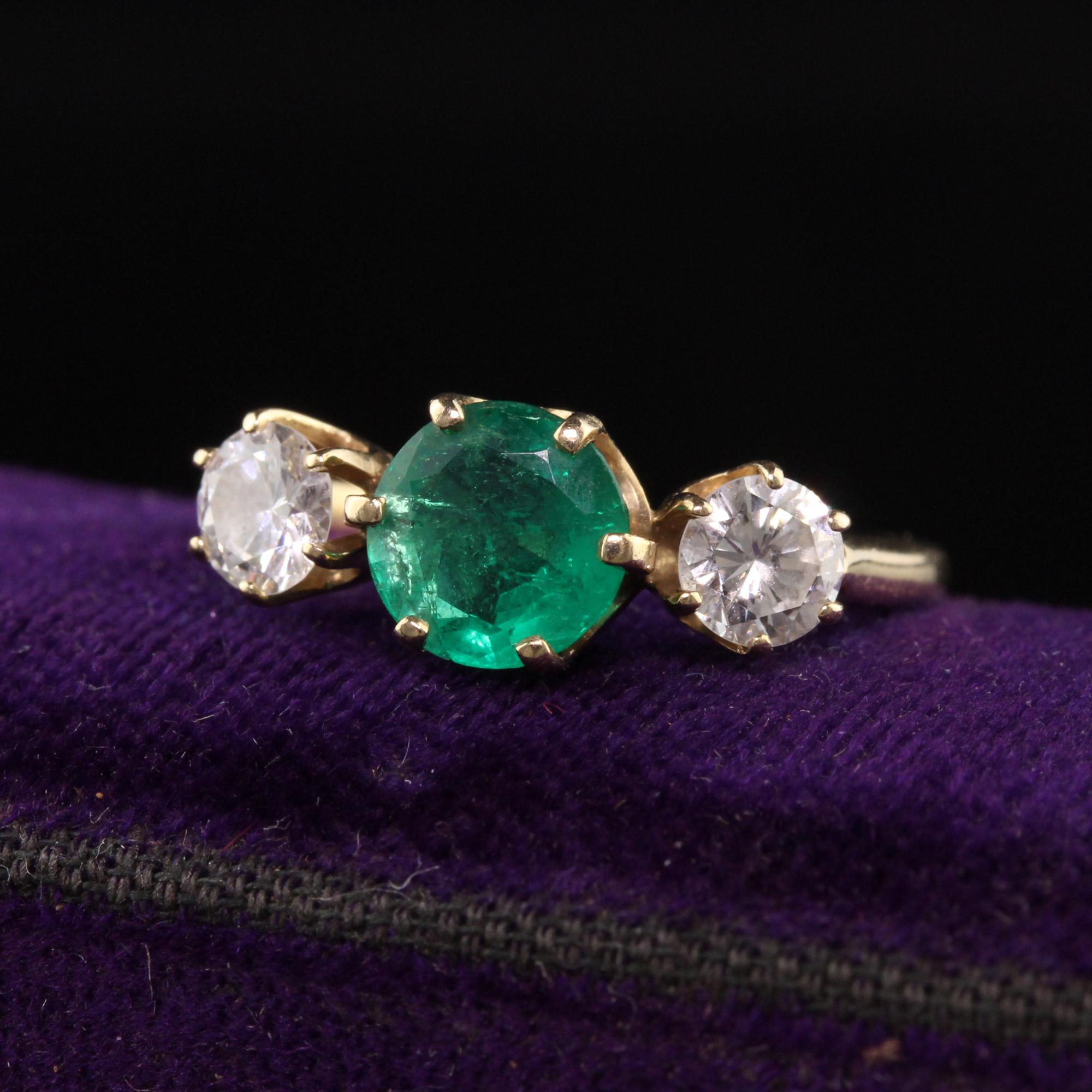Schöner Vintage Retro 14K Gelbgold Smaragd und Diamant Dreistein-Ring. Dieser klassische Ring ist aus 14 Karat Gelbgold gefertigt. In der Mitte befindet sich ein schöner grüner Smaragd, in der Mitte zwei weiße und saubere Diamanten auf jeder