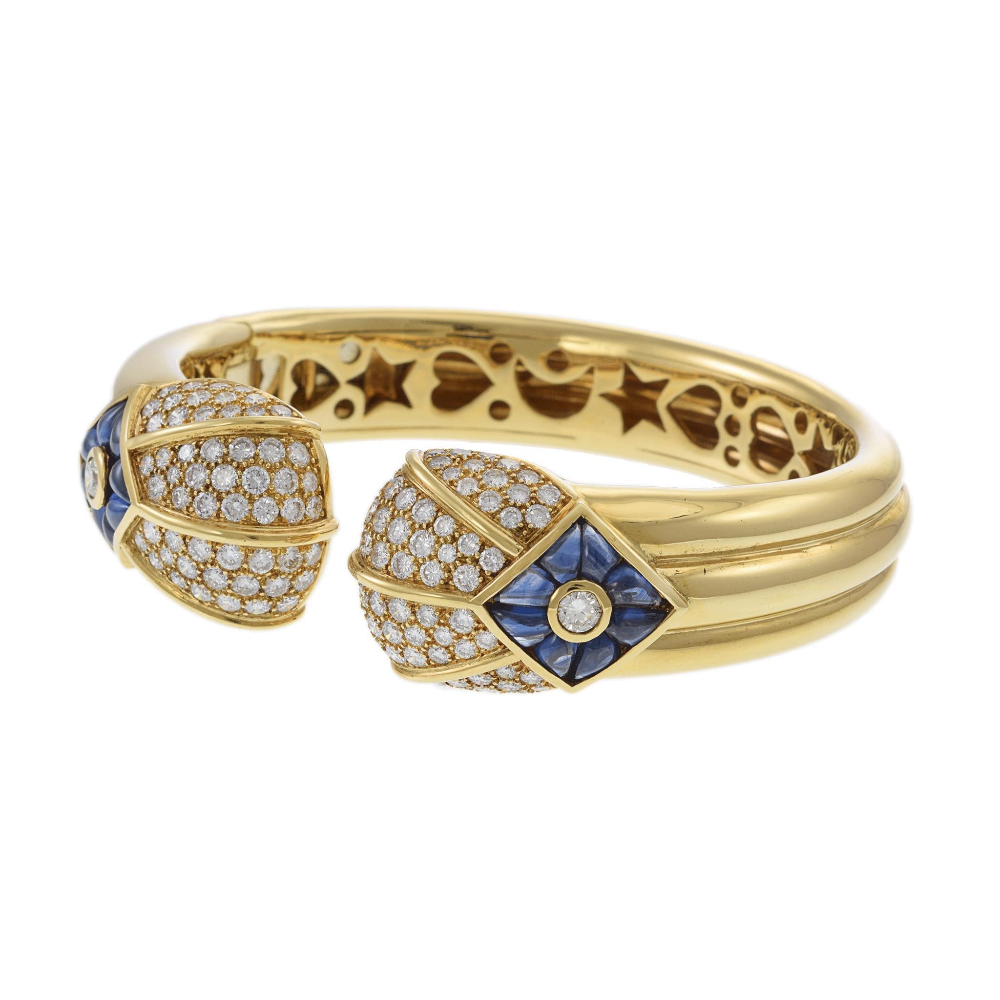 Retro Yellow Gold Diamond and Sapphire Bangle Bracelet is a statement of elegance.

This luxurious piece showcases 4.5 carats of round, white diamonds, known for their VS2 clarity and F color grade.

The bracelet is adorned with 4.0 carats of blue