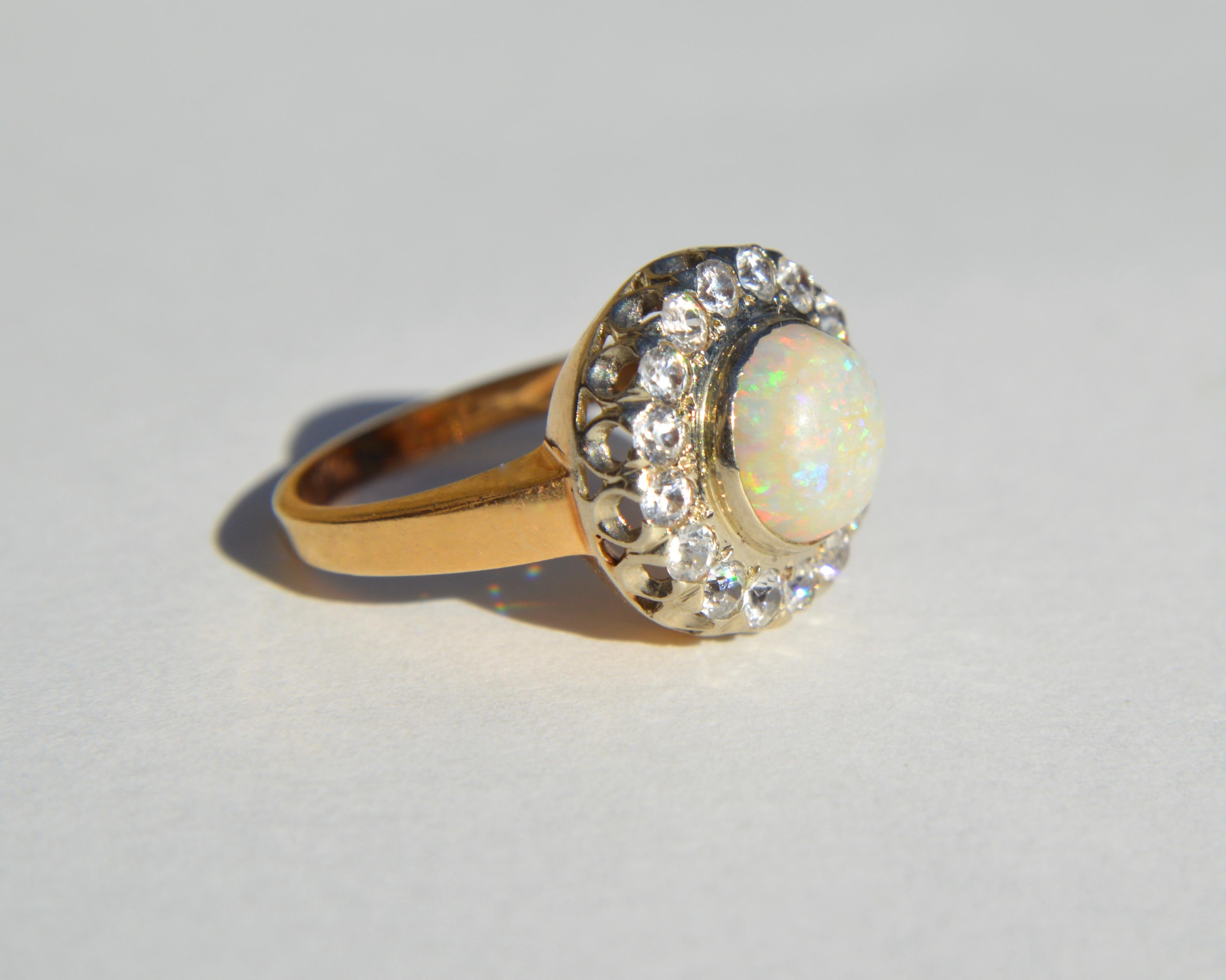 Beautiful retro 1940s 2.04 carat opal cabochon with a 16 diamond halo in solid 14K yellow gold. In good condition. Each single cut VS1 clarity H diamond measures 2mm (.03 carat). The Australian opal has an array of rainbow fiery flecks. Size 5.5,