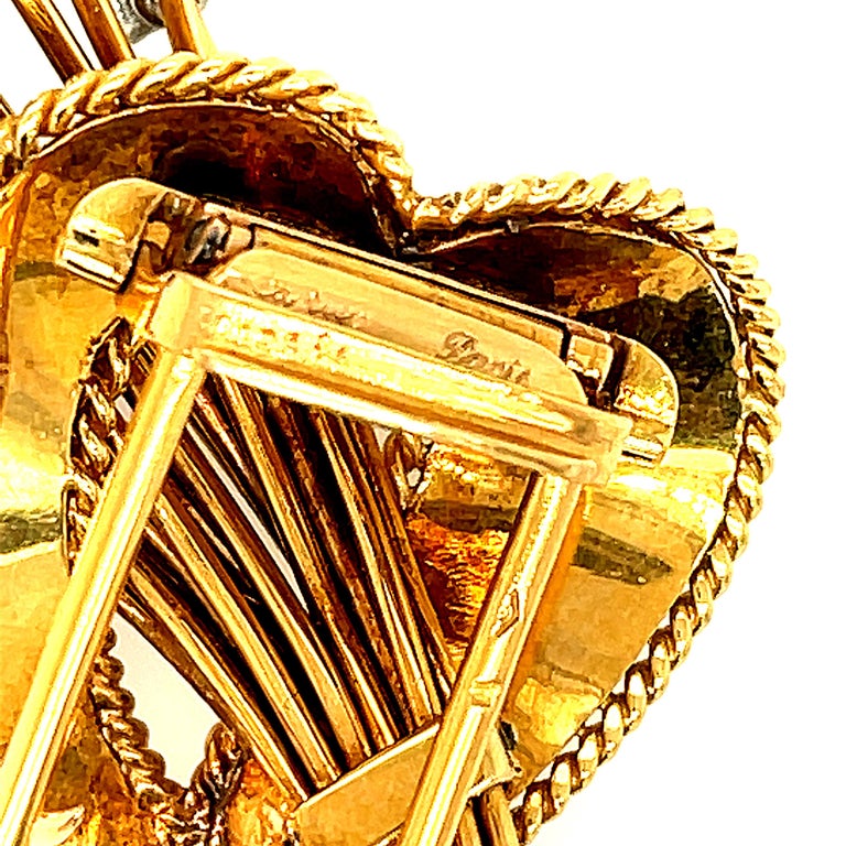 A charming 18k gold heart shaped diamond spray brooch by Cartier, circa 1950. This pretty fluted dimensional heart is open and through it a spray of diamonds on stems shoot through the heart. It is a whimsical design with movement and dimension. The