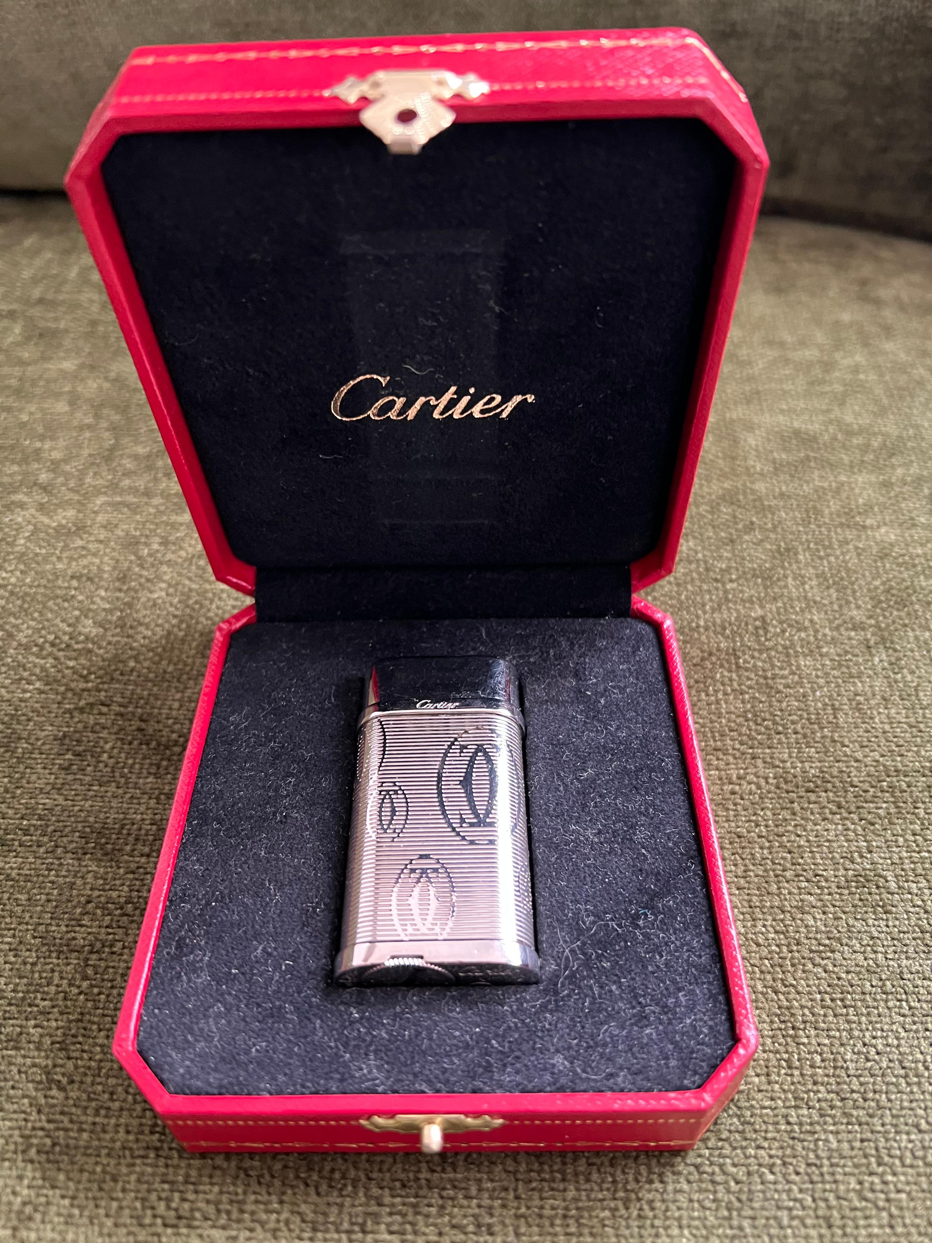 Le Must De Cartier Lighter 
“C Logo”  Cartier Silver Palladium Finish 
Comes with original Cartier Luxury Red case with black velvet interior
In mint exterior and working condition 
Circa 2000
In great condition 
All original parts 
Chic, retro and