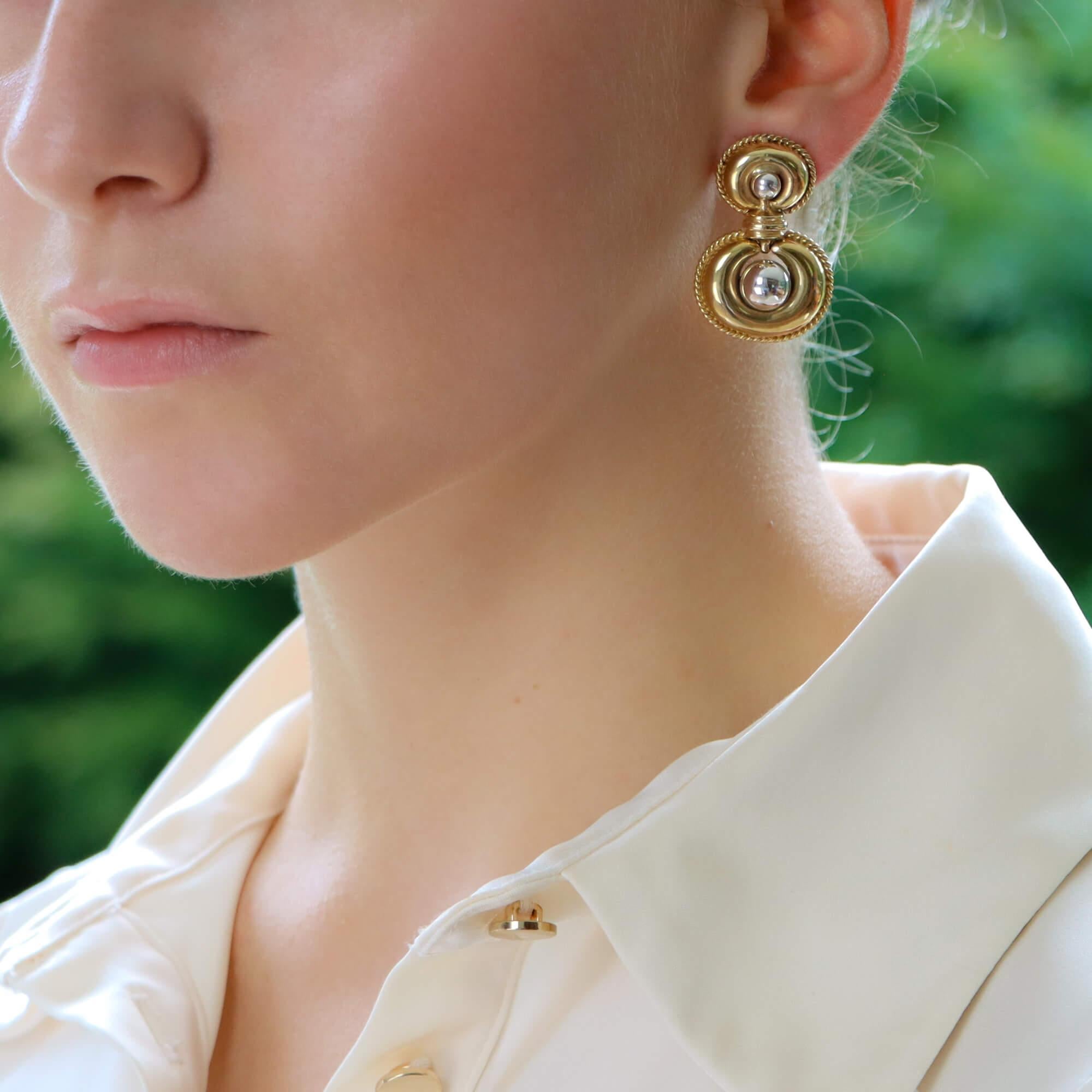 A stylish retro pair of door knocker inspired earrings in 9k yellow and white gold.

Each earring is composed of a unique retro design; with yellow gold ropework and polished white gold balls to the centre. The bottom aspect of the pair is