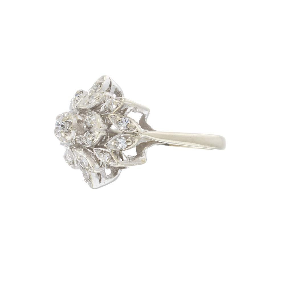 This stunning Retro era cluster ring is a vintage treasure with timeless elegance. Crafted in 14KT white gold, the ring features an intricate floral design set with brilliant round diamonds totaling approximately 0.55 carats. Each marquise-shaped
