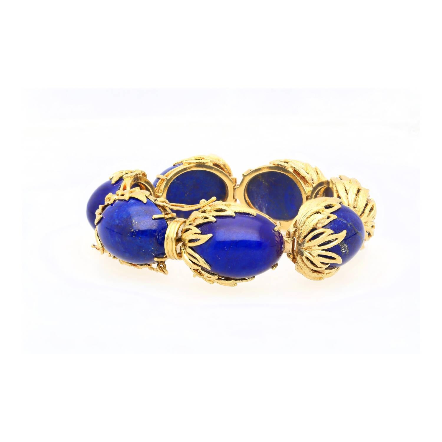 Retro Lapis Lazuli Bracelet in Floral 18K Yellow Gold.

This bracelet punctuates seven individual lapis lazuli gemstones, each with an oval shape and vivid blue saturation, with a carat weight of 2.50 total. The stones are secured in a prong setting