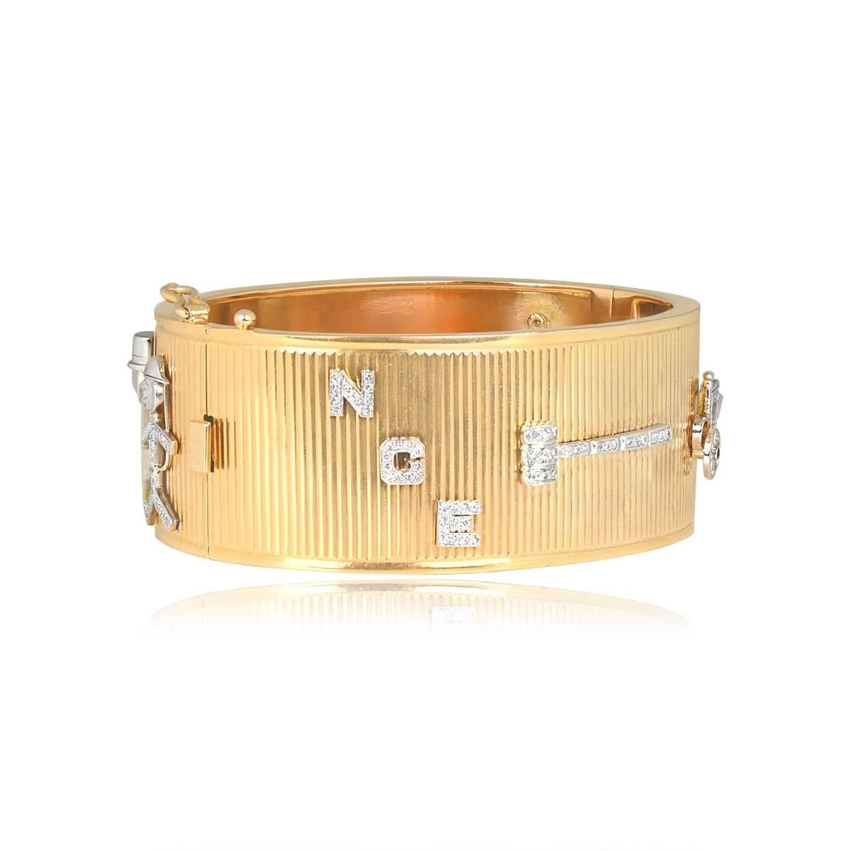 A Retro-era bracelet with a 14k yellow gold bangle and platinum Art Deco charms adorned with single-cut diamonds. Charms include the letters N G E, a judge’s gavel, a detailed carriage with emerald accents, a second gavel, a courthouse, a car, and