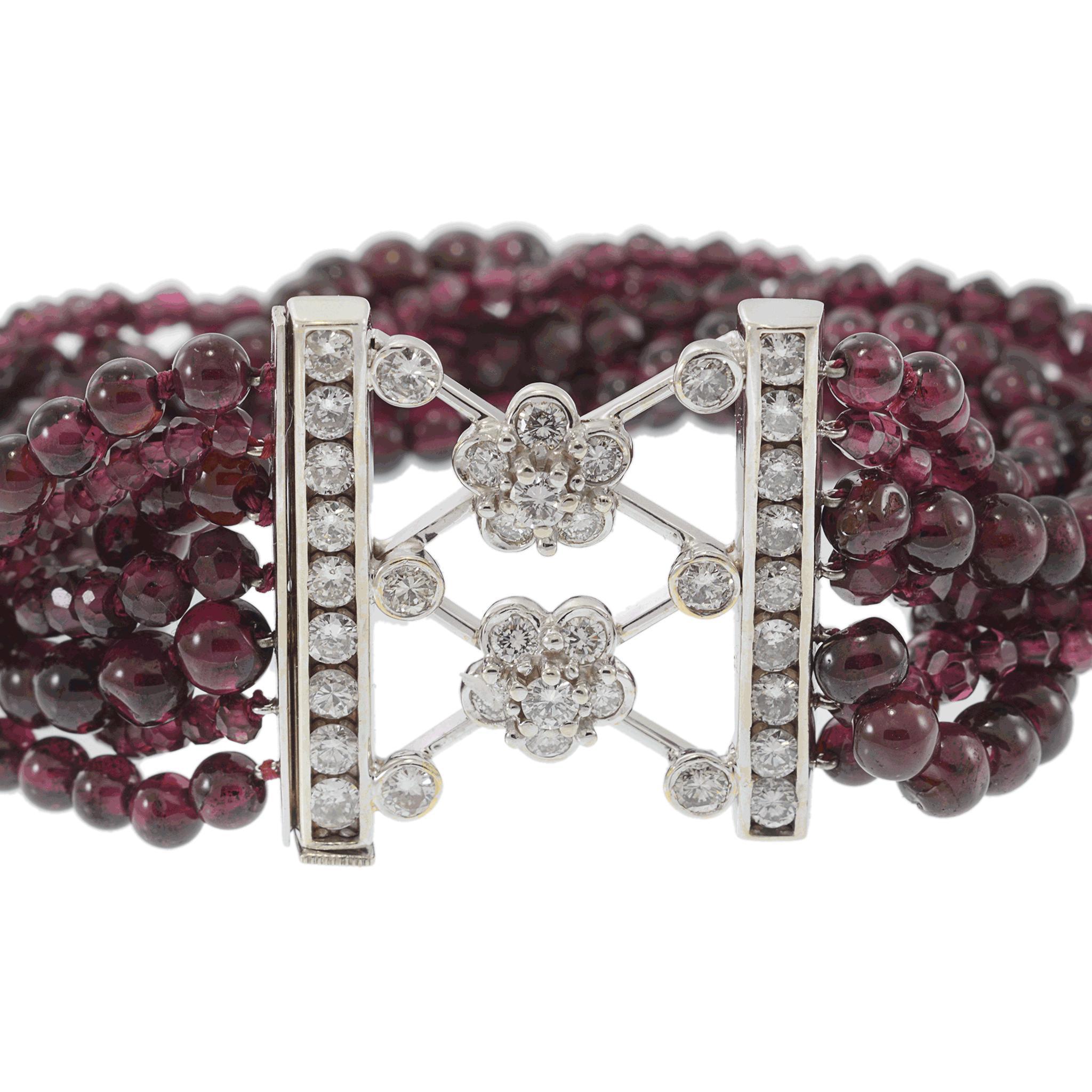 Elegante Pulsera Retro de Granate y Diamantes de Mediados del Siglo XX. Esta exquisita pulsera presenta múltiples hileras de cuentas de granate rojo intenso, bellamente contrastadas por un llamativo cierre de oro blanco adornado con brillantes