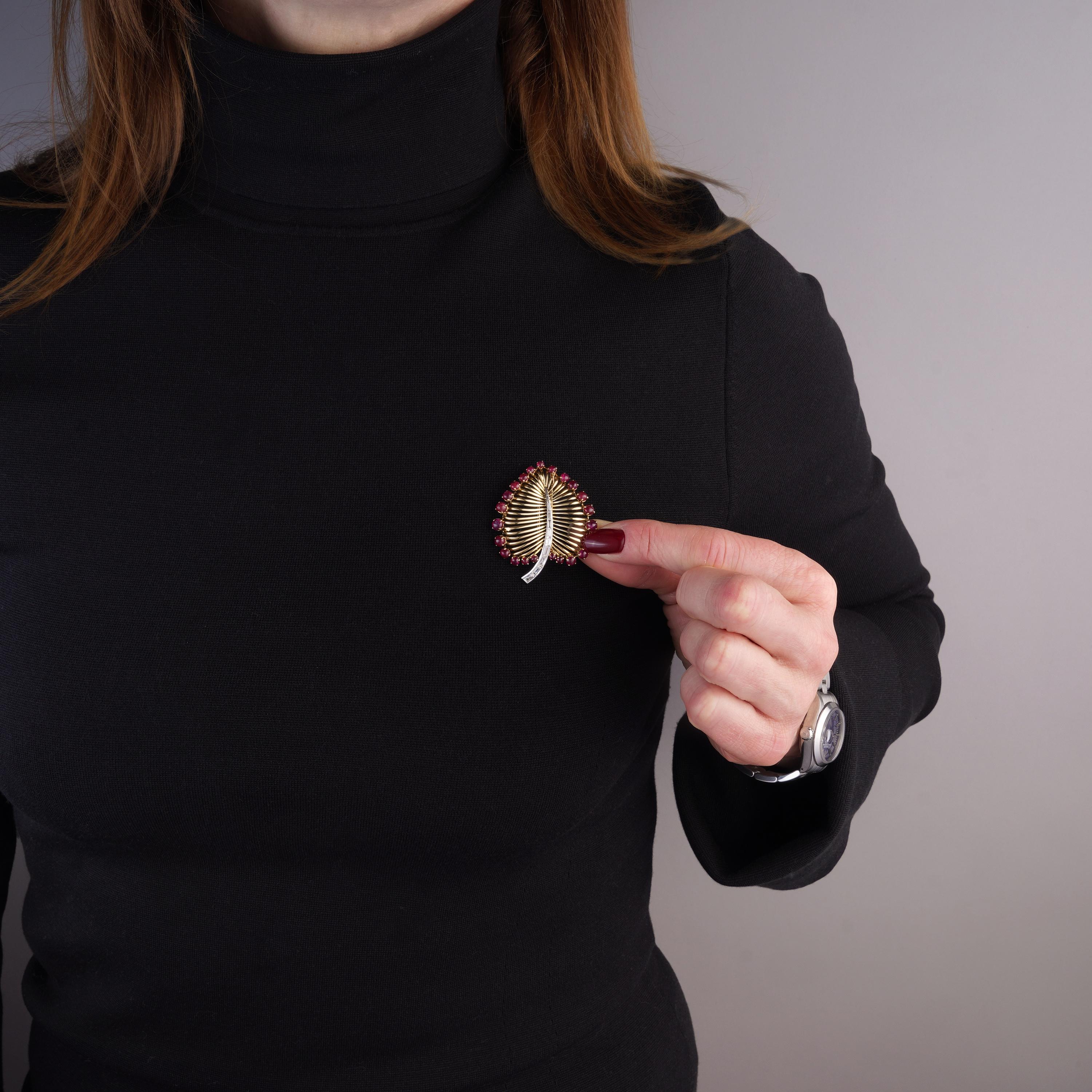 Broche vintage retro de oro y platino con forma de hoja de diamante talla baguette de 1,74 cts. y rubí cabujón de 3,71 cts.

El diseño: El diseño sigue una estética retro-modernista, de los años 50 a 60, que refleja las formas atrevidas y