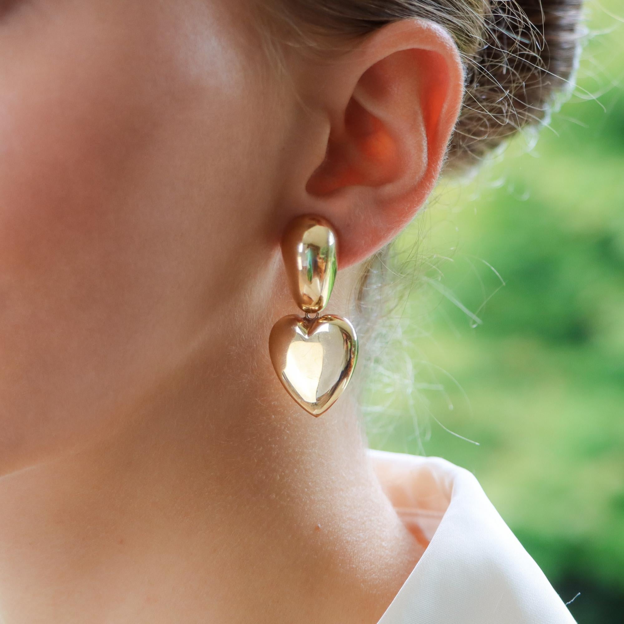 A stylish retro pair of chunky heart drop earrings in 9k rose gold.

Each earring is composed of a unique retro design; to the top of the ear is a chunky panel which suspends a large polished gold heart. The heart is articulated which allows the