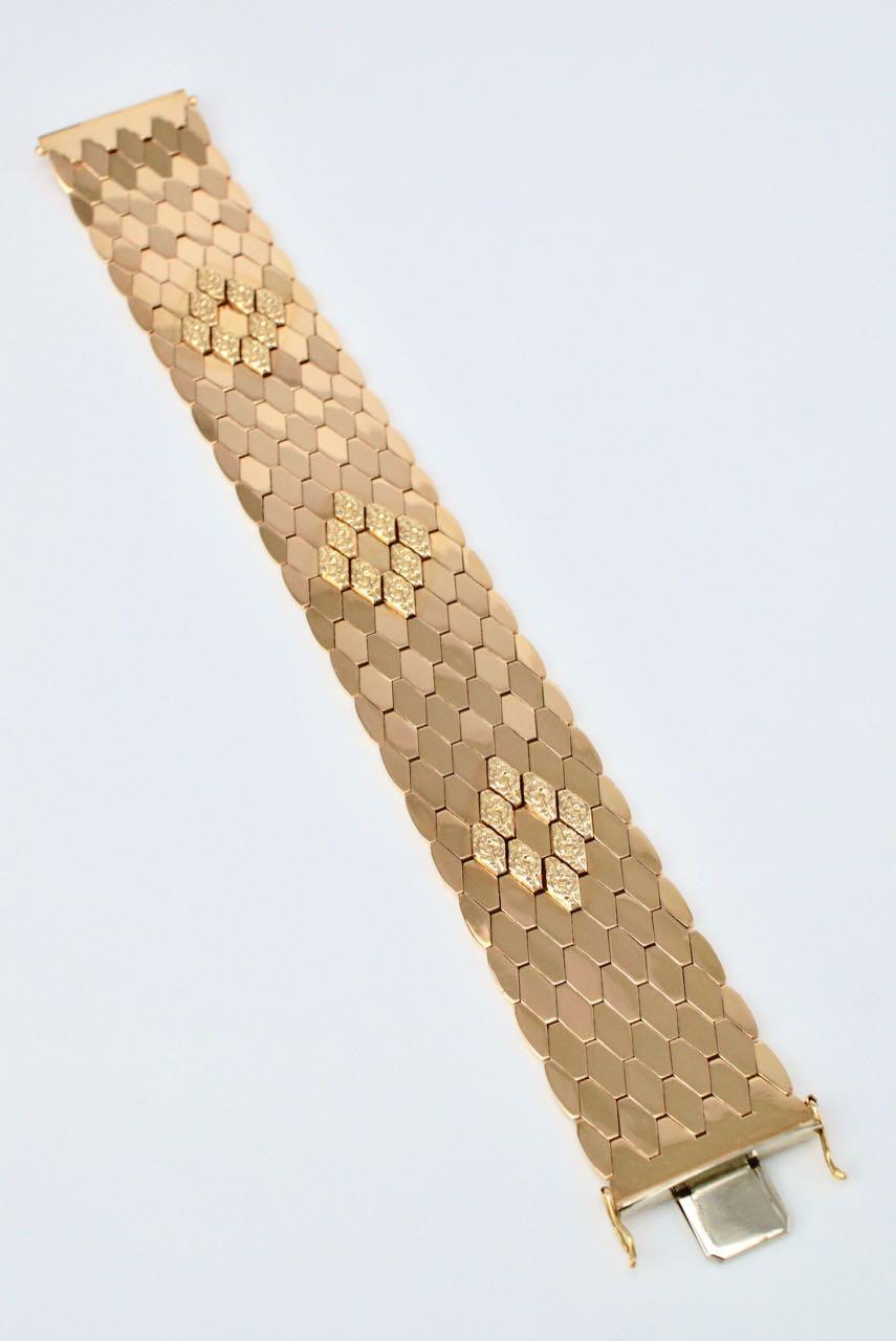 A striking Retro design bracelet of a honeycomb pattern of hinged interlocking diamond shaped links in 18k gold to form a wide band with three raised diamond shaped motifs to the centre, finished with a box clasp closure and double figure of eight