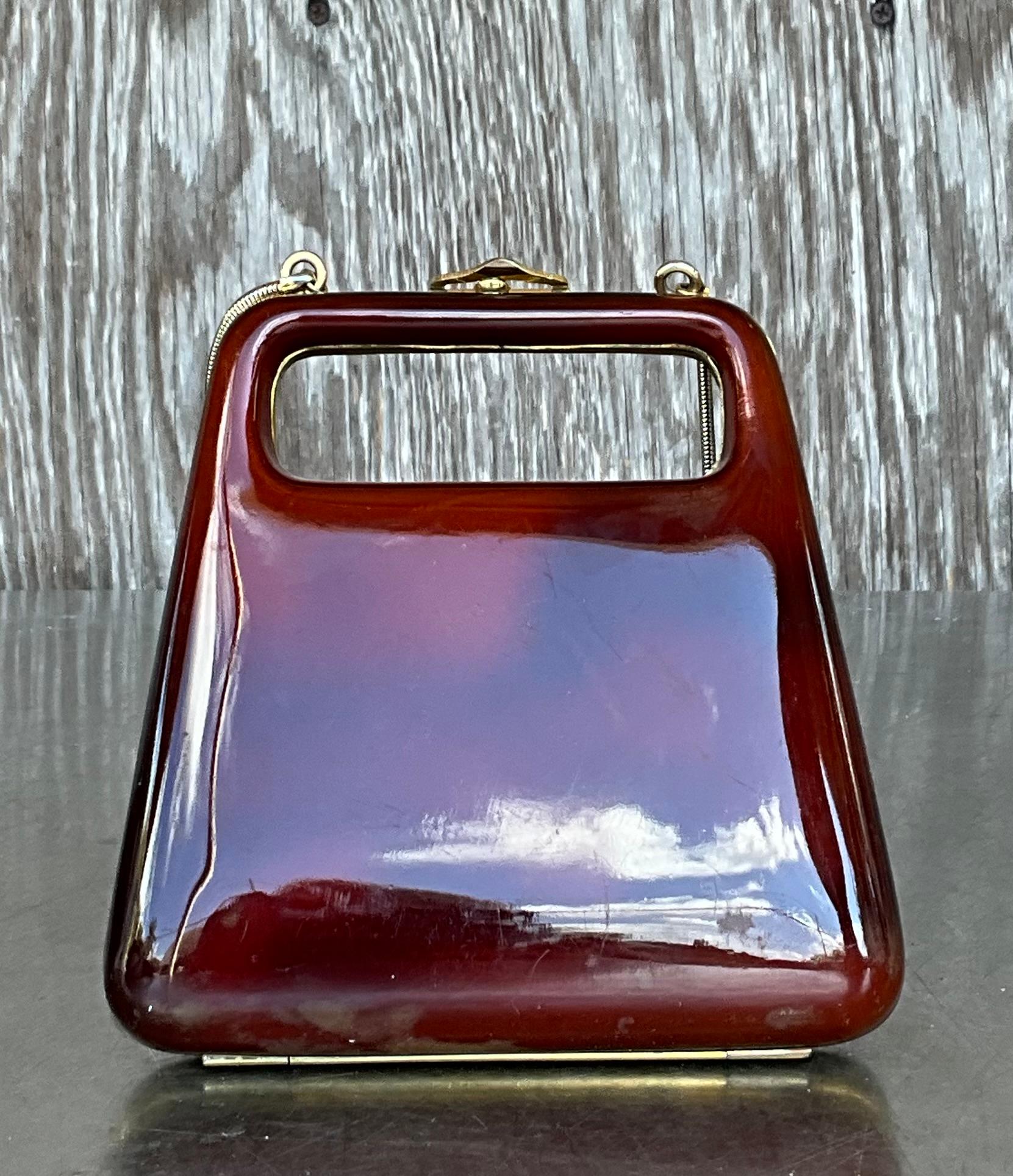 A Vintage Retro Lucite Clutch is a refined and glamorous accessory from the mid-20th century, often associated with the 1940s to 1960s. Lucite, a clear, durable acrylic resin, became a popular material for fashion accessories during this period due